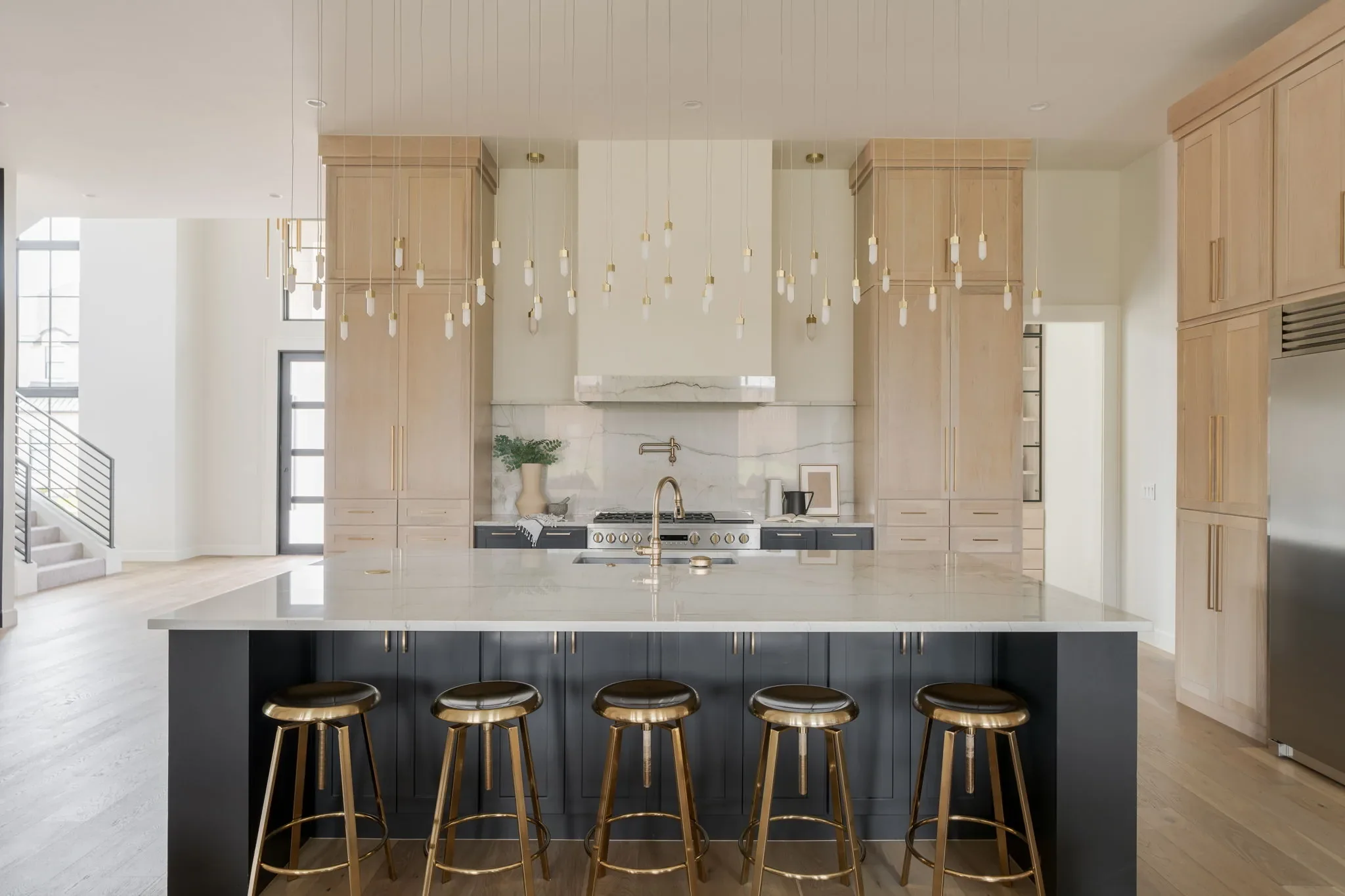 White oak kitchen with a charcoal island and five counter stools
