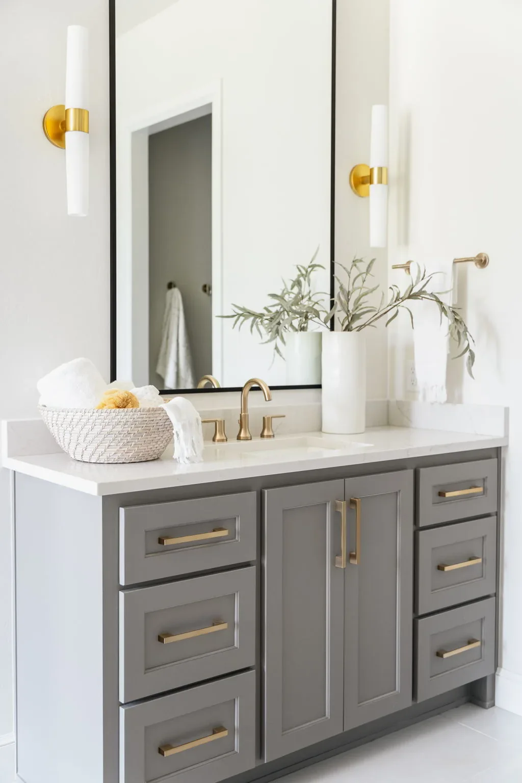 Gray bathroom vanity with brass fixtures and mirrored cabinets