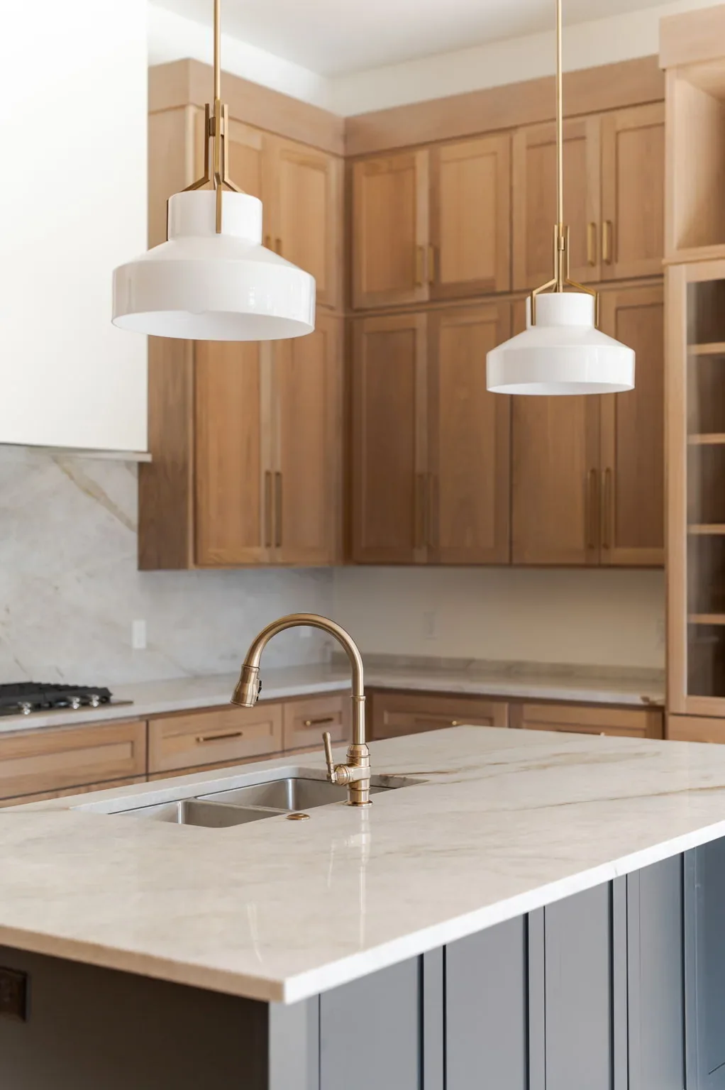 Marble-look kitchen island beneath white pendant lights