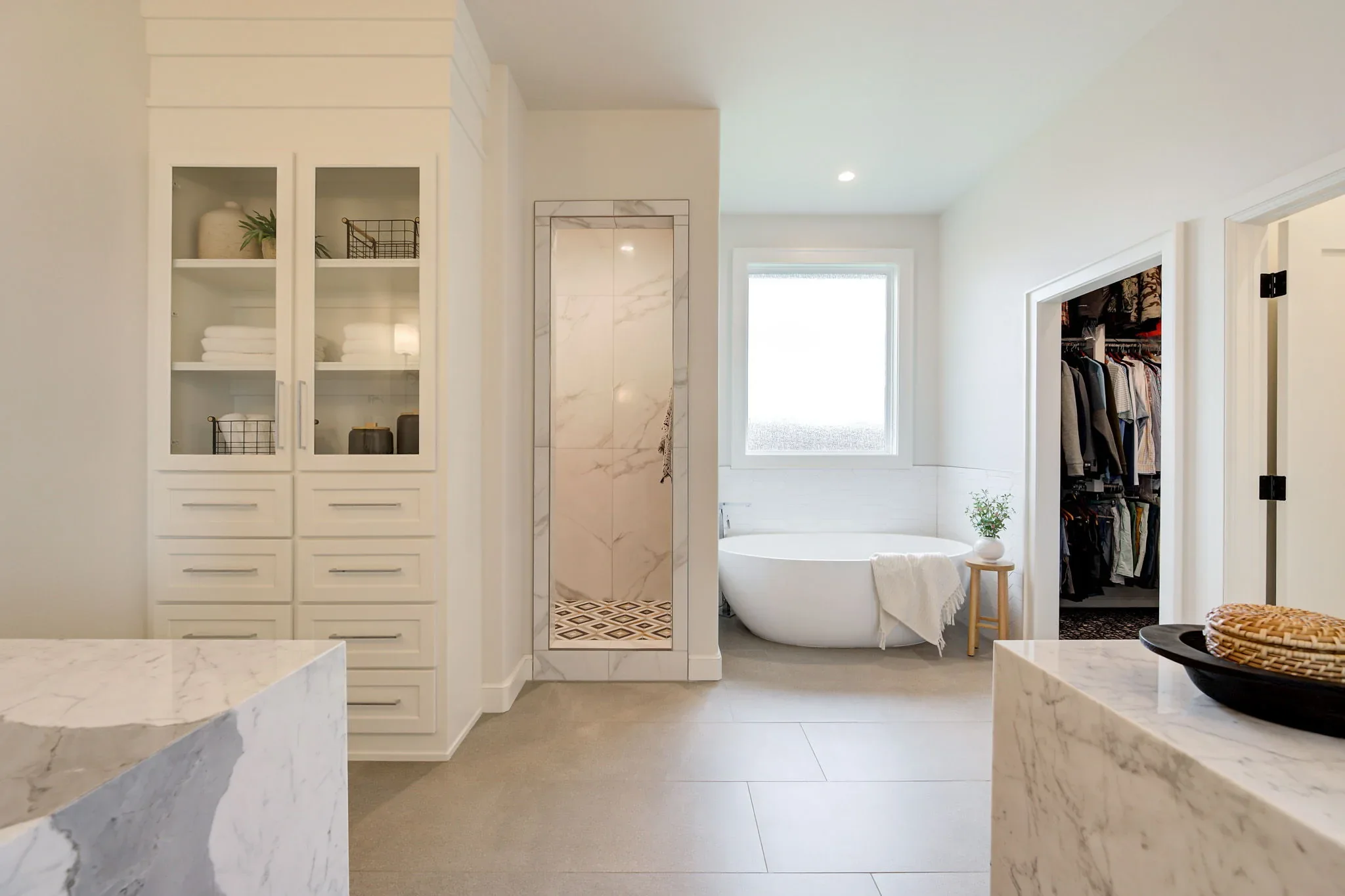 Primary bathroom suite with built-ins, marble counters, and freestanding tub