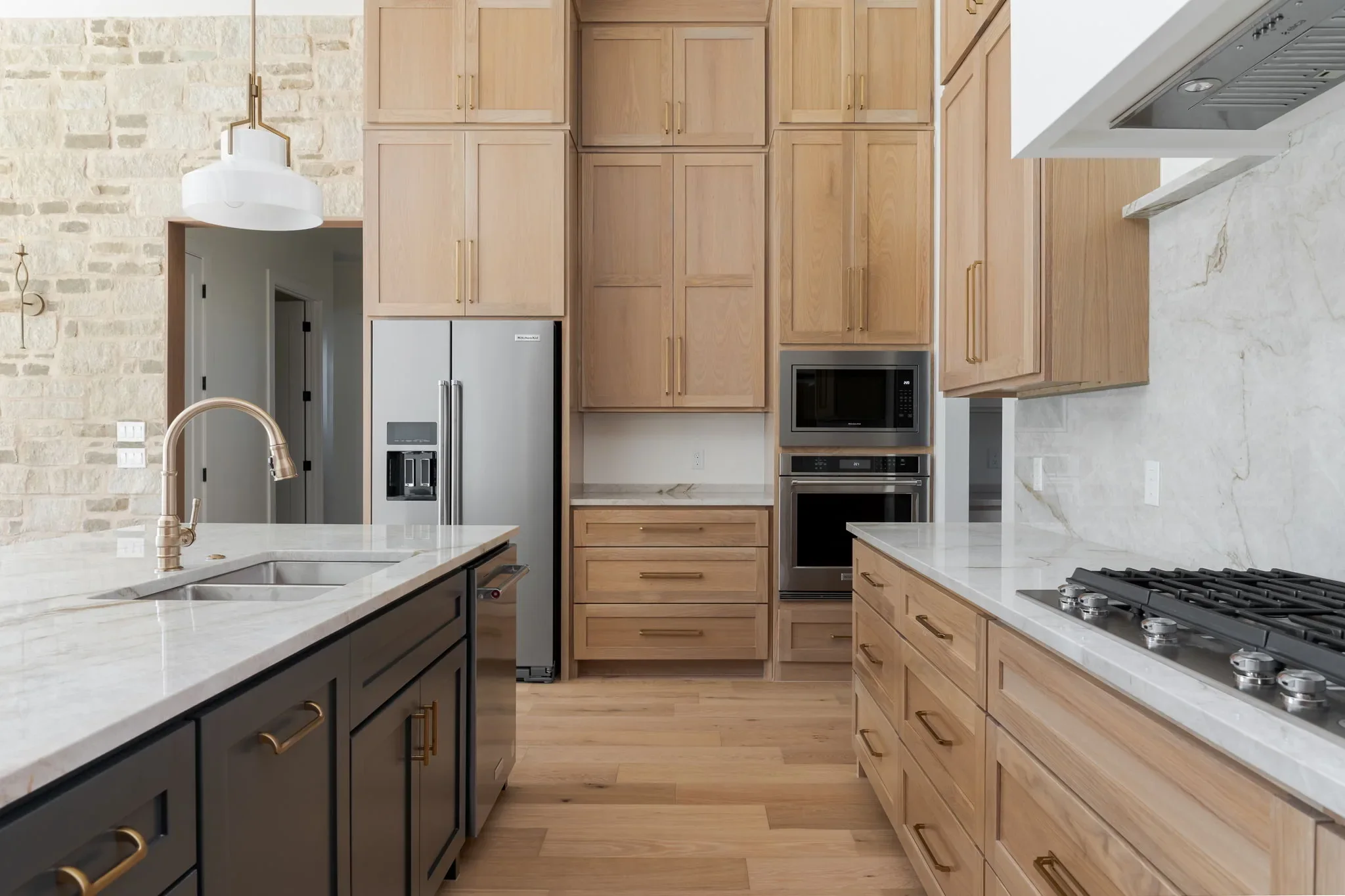 Oak kitchen cabinetry with a black island and stone wall