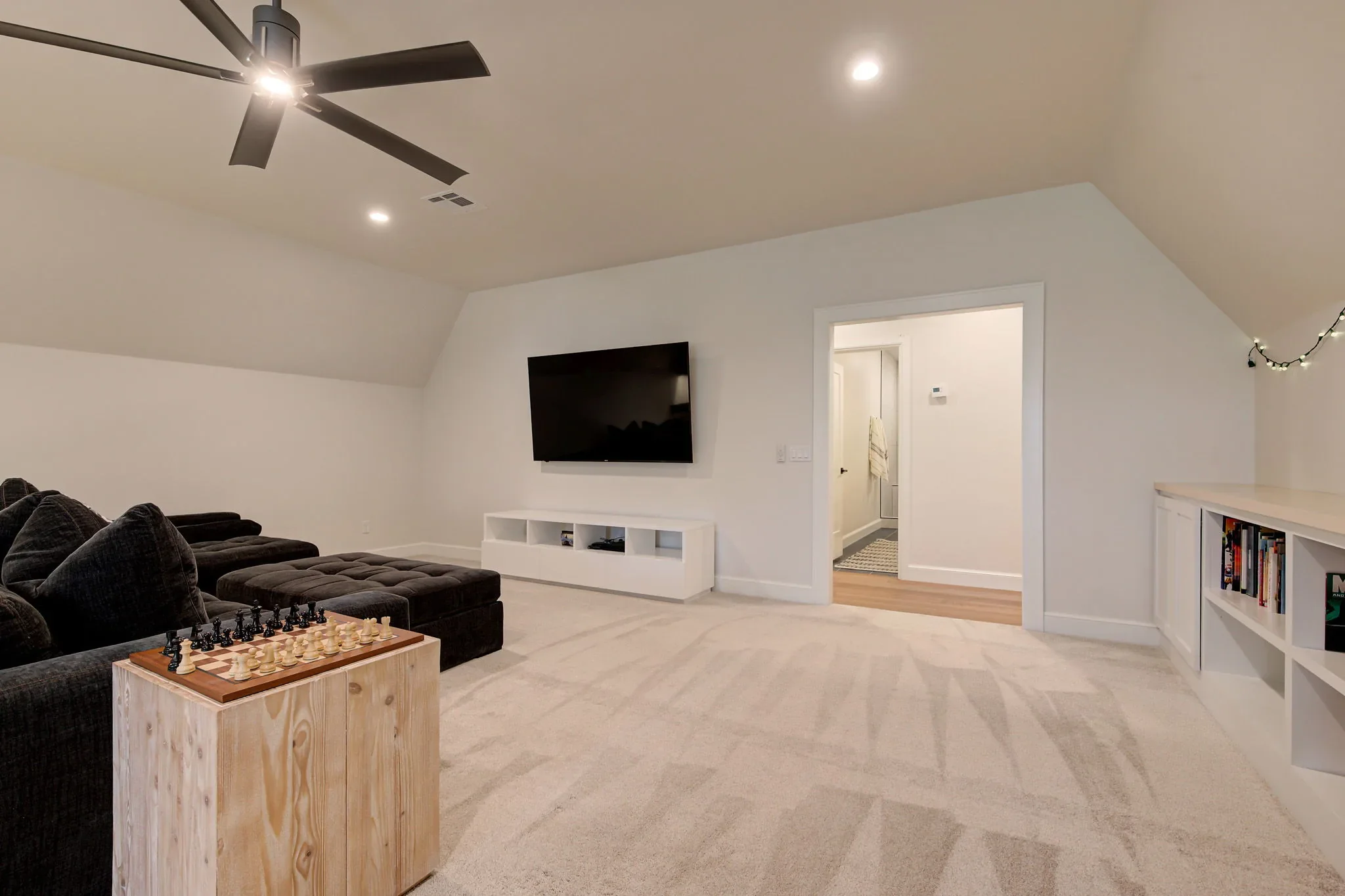 Upstairs media room with sectional, television, and built-in bookcases