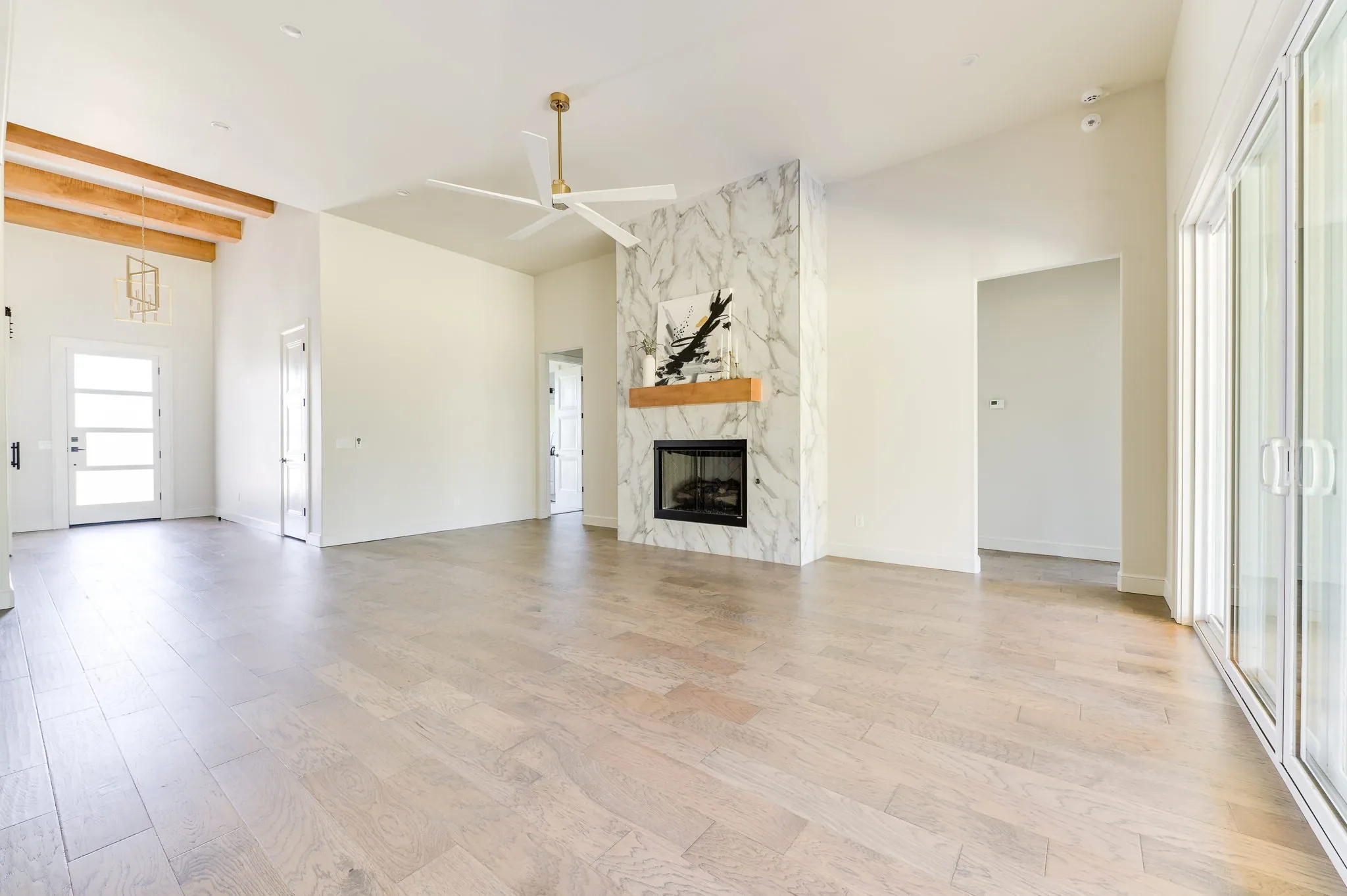 Great room with a marble fireplace, wood beams, and sliding doors