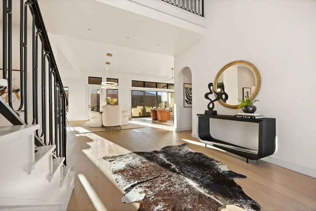Foyer with open staircase, arched mirror, and cowhide rug
