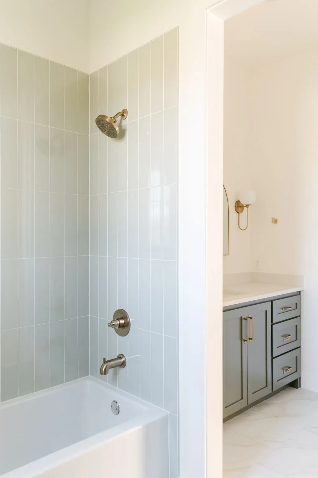 Pale green tiled tub-shower beside a dark vanity