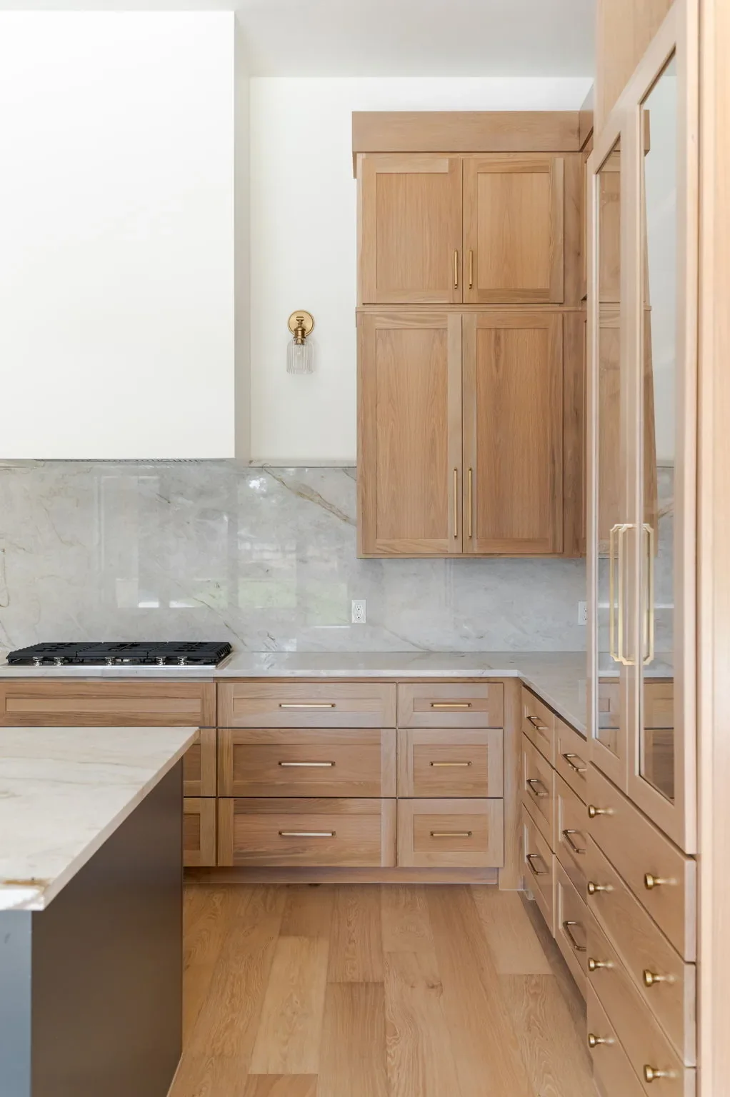 Oak kitchen cabinetry, gas range, and marble-look backsplash