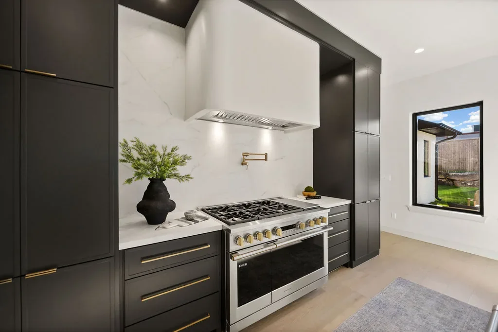 Chef's range beneath a white hood and charcoal cabinetry