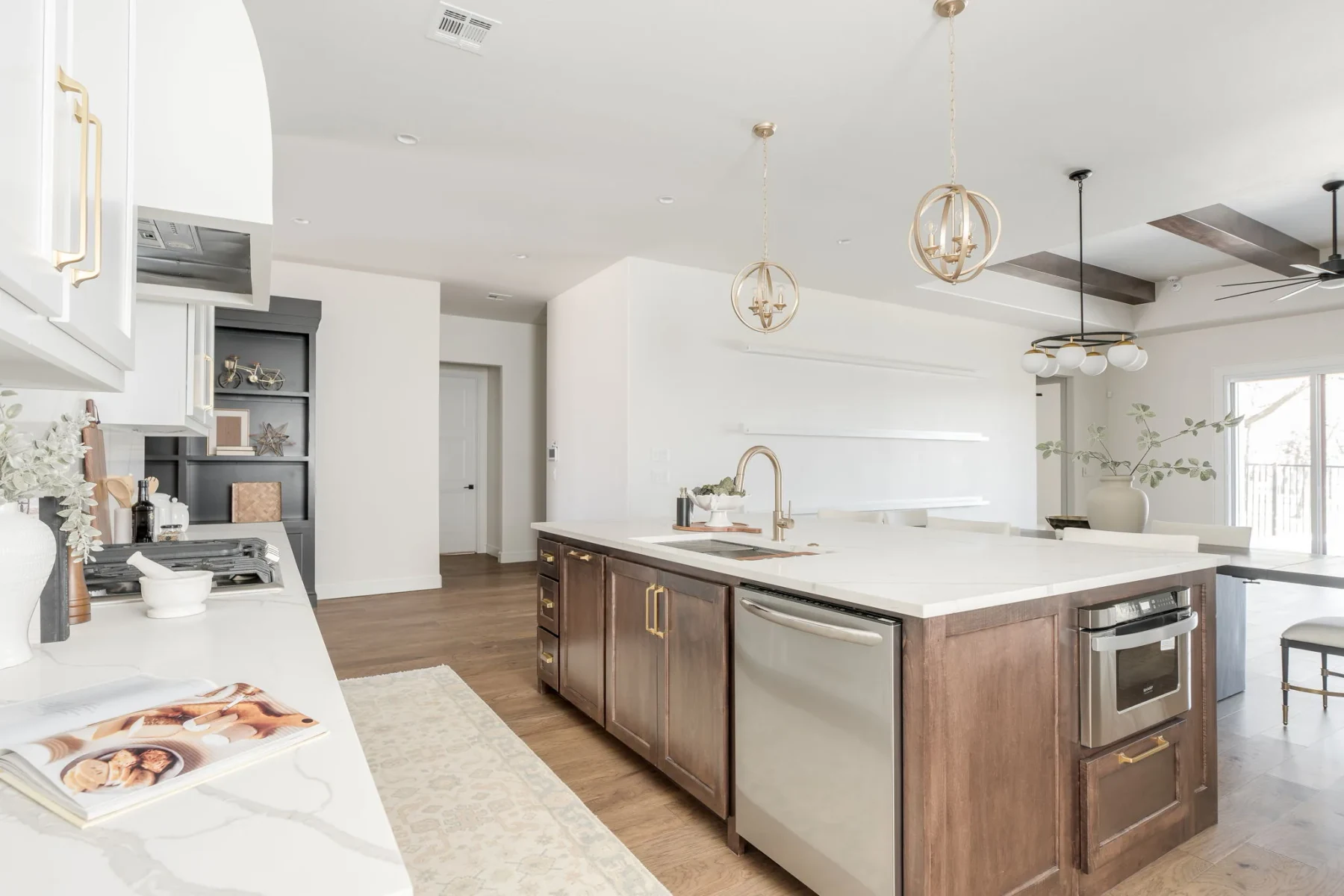 White kitchen with a dark wood island, brass pendants, and double ovens