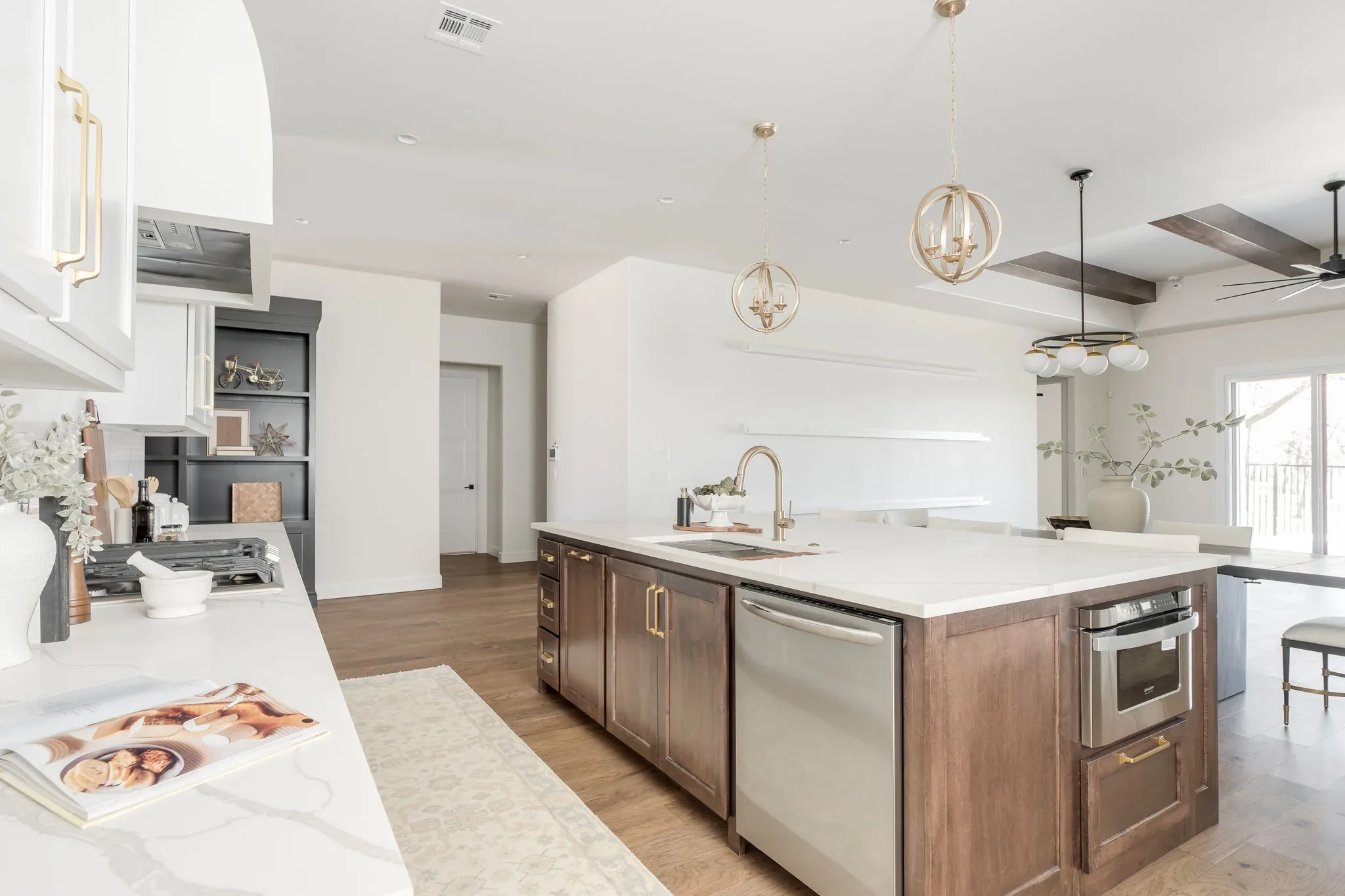 White kitchen with a dark wood island, brass pendants, and double ovens