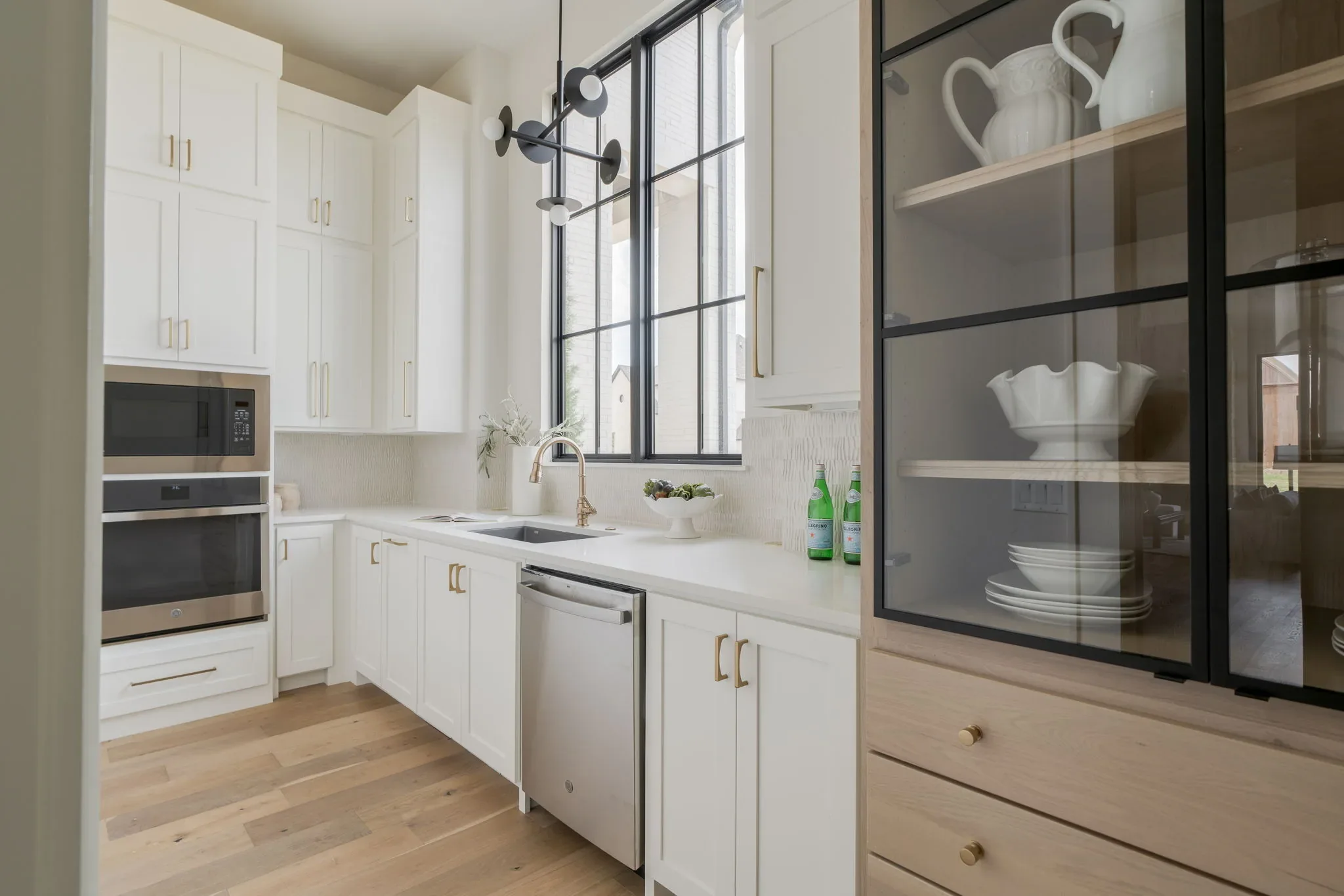 Prep kitchen with white cabinetry, large windows, and a glass display cabinet