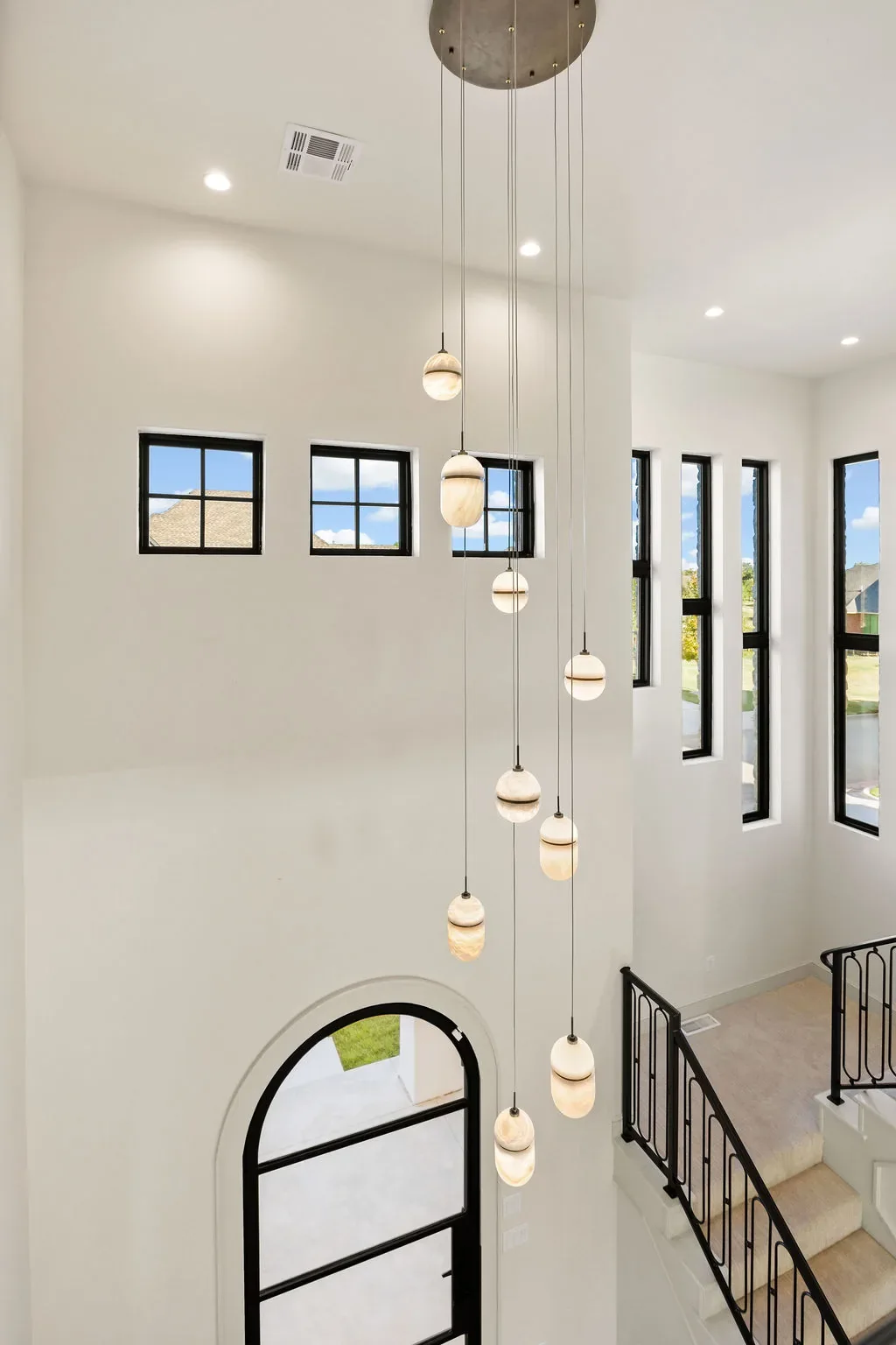 Double-height stairwell with cascading white pendant lights