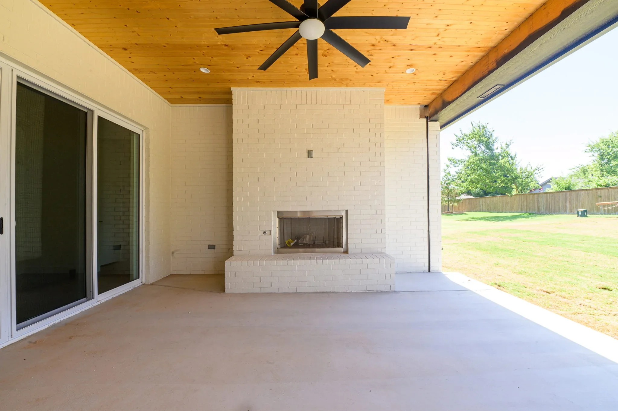 Covered rear patio with a wood ceiling and outdoor fireplace
