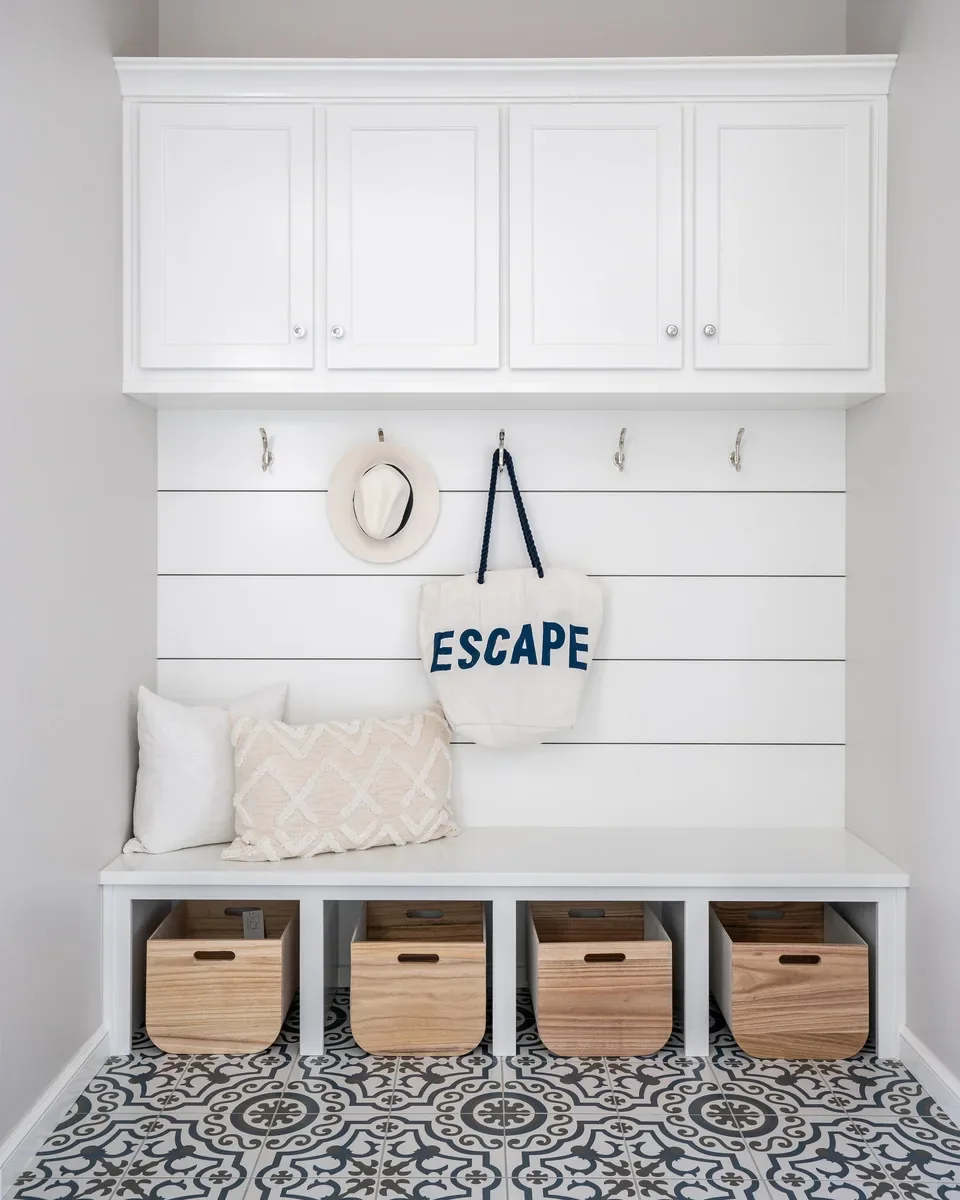 Mudroom bench with white cabinetry and patterned tile floor