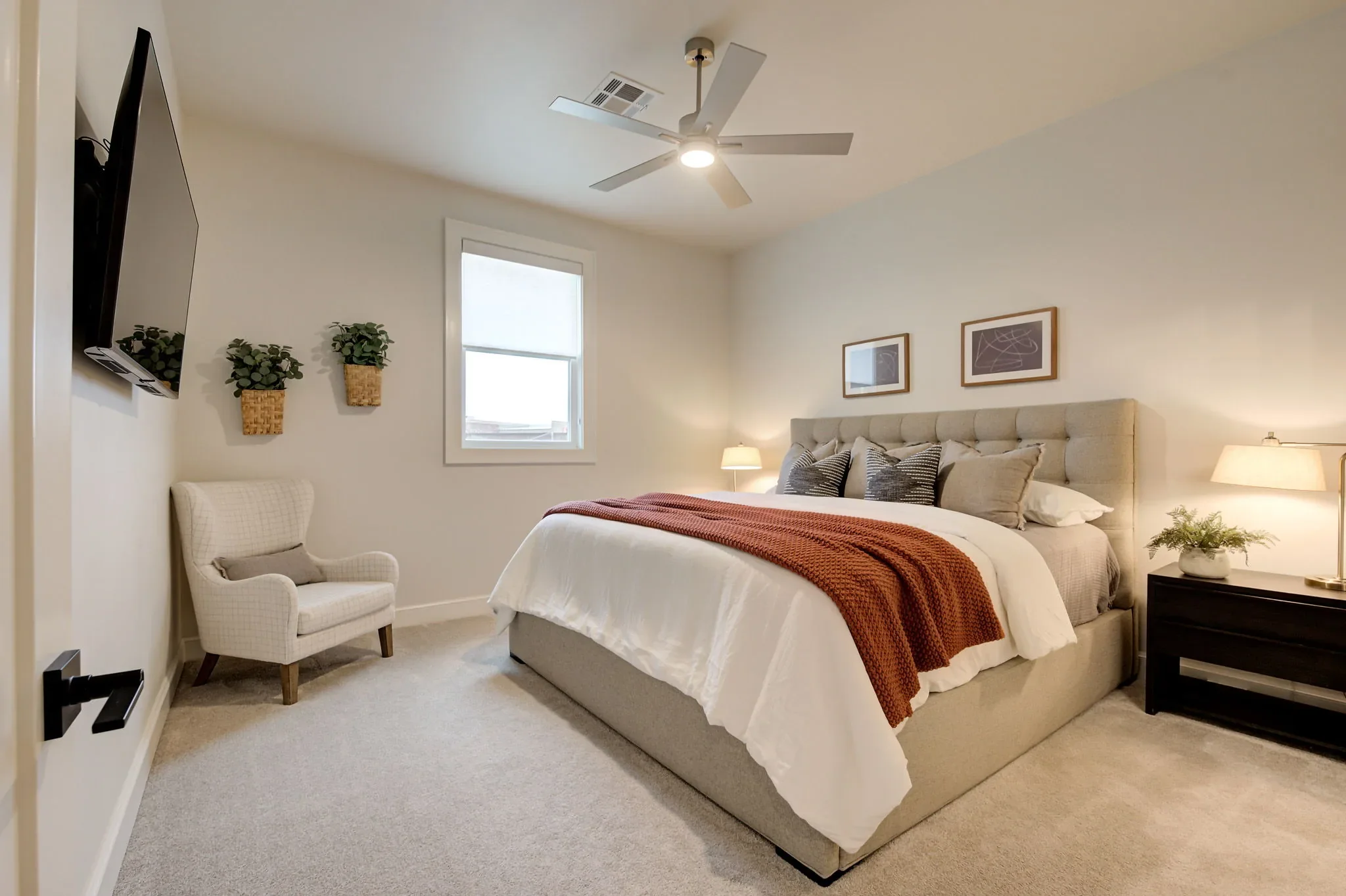 Guest bedroom with neutral bedding and rust-colored throw