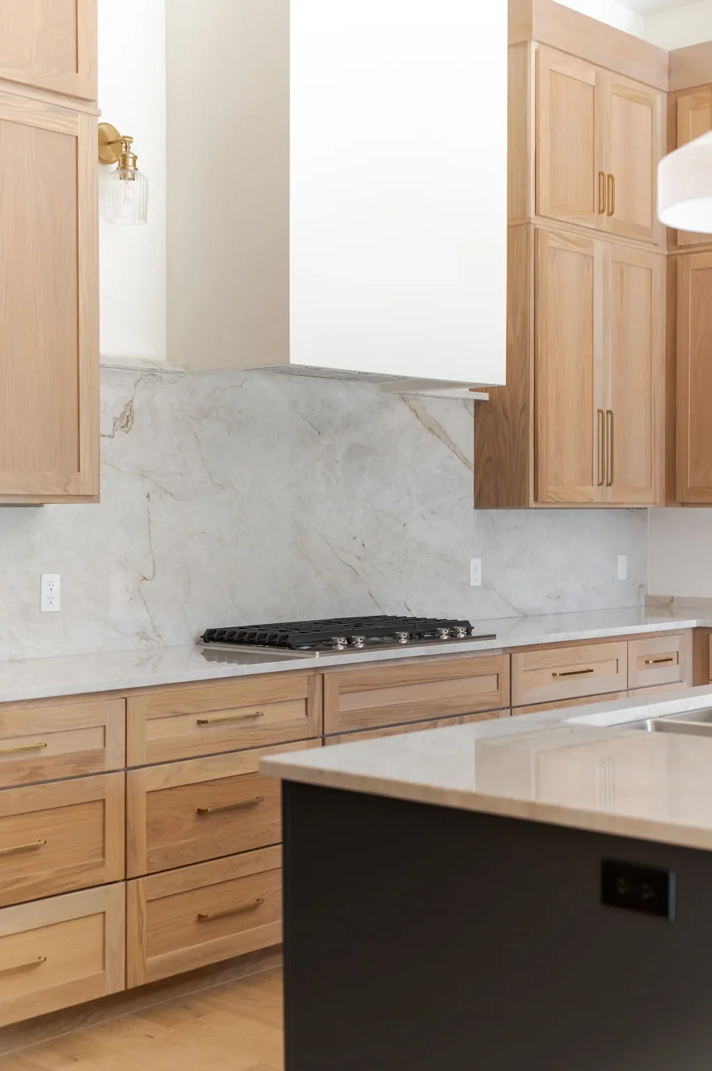 Gas range framed by oak cabinetry and a black island
