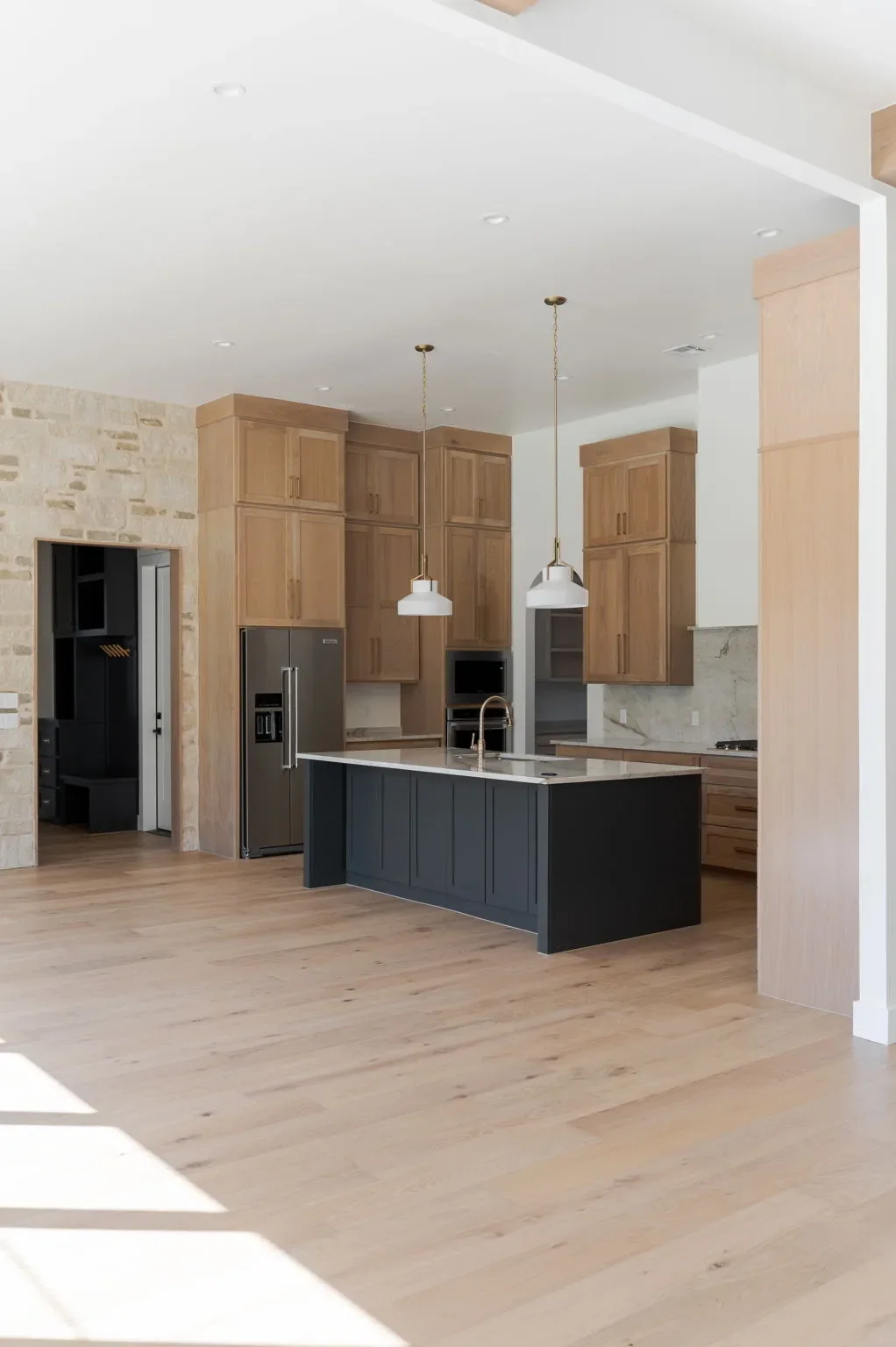Oak kitchen with a black island and stone accent wall