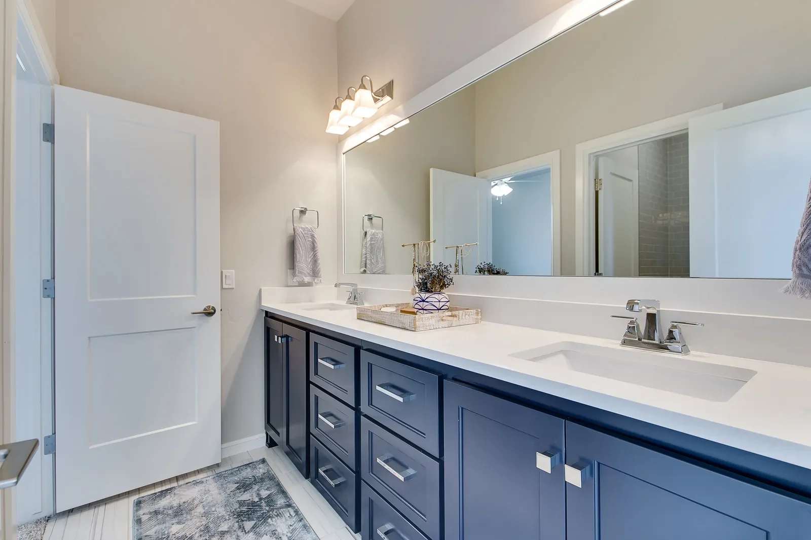 Bathroom with navy double vanity and wall-to-wall mirror