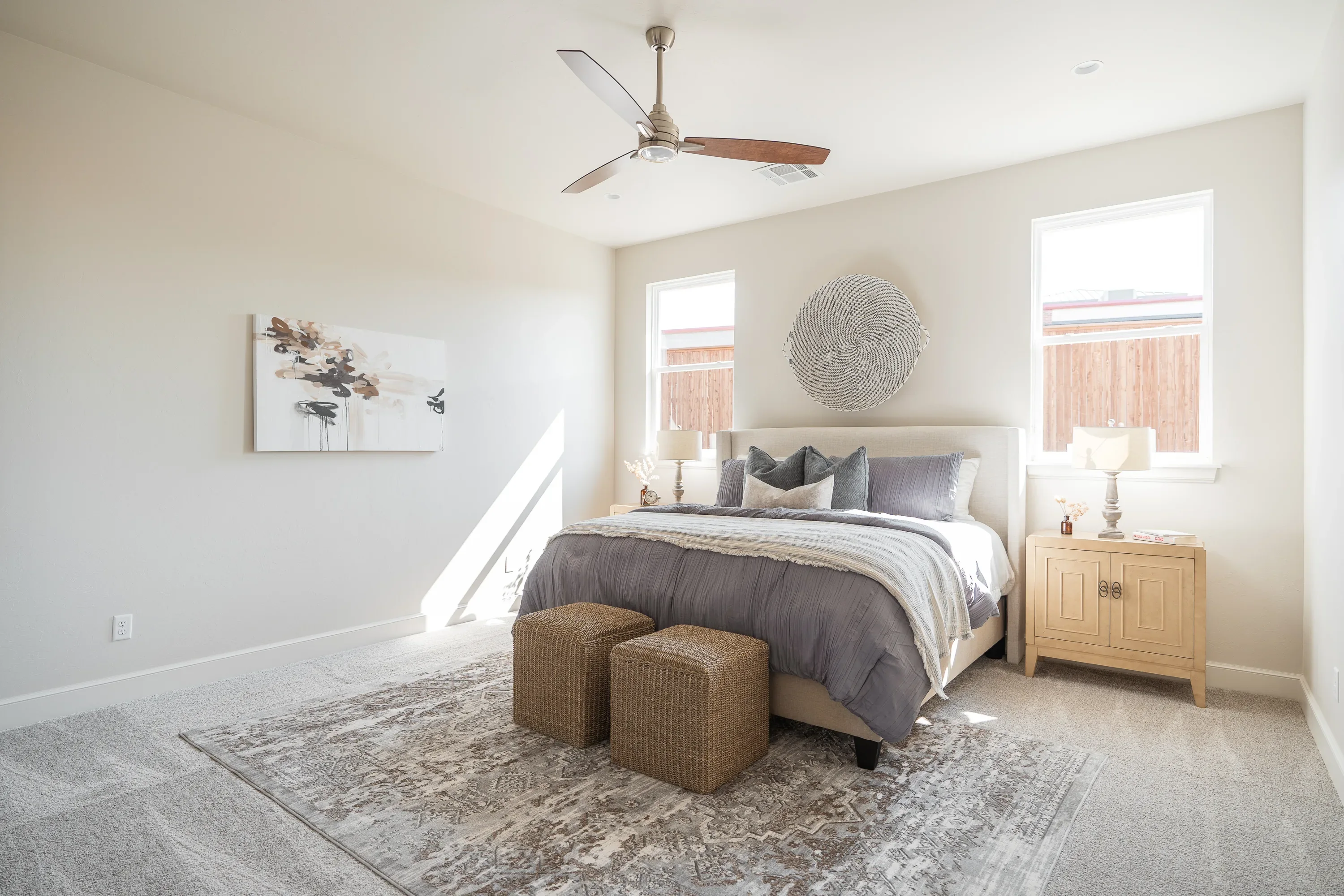 Bright guest bedroom with neutral bedding and woven benches