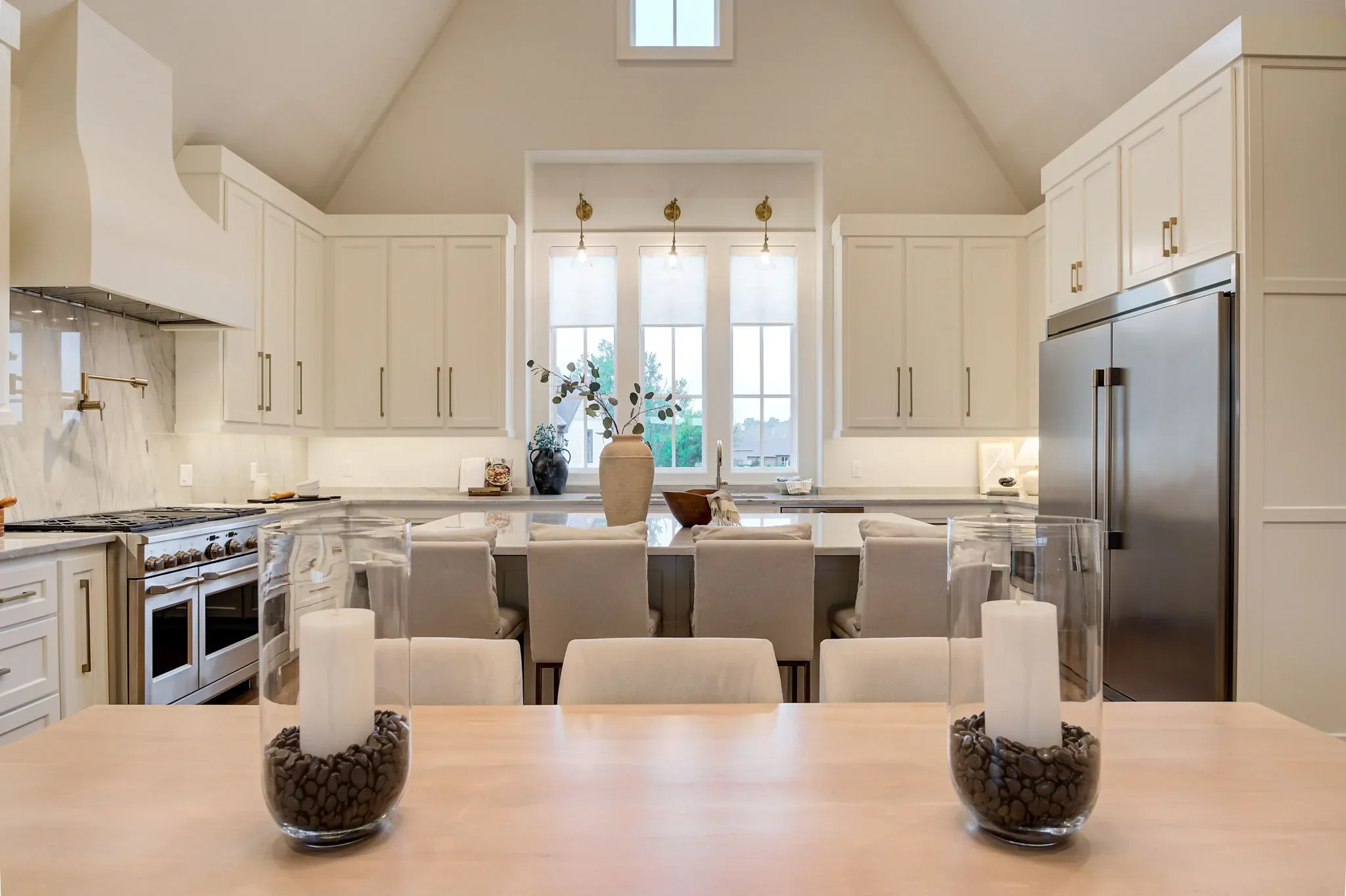 White chef's kitchen with marble island and vaulted ceiling