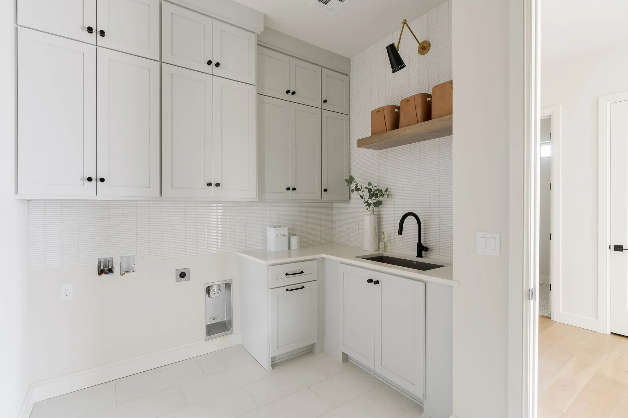 Laundry room with white cabinetry, a utility sink, and open wood shelves