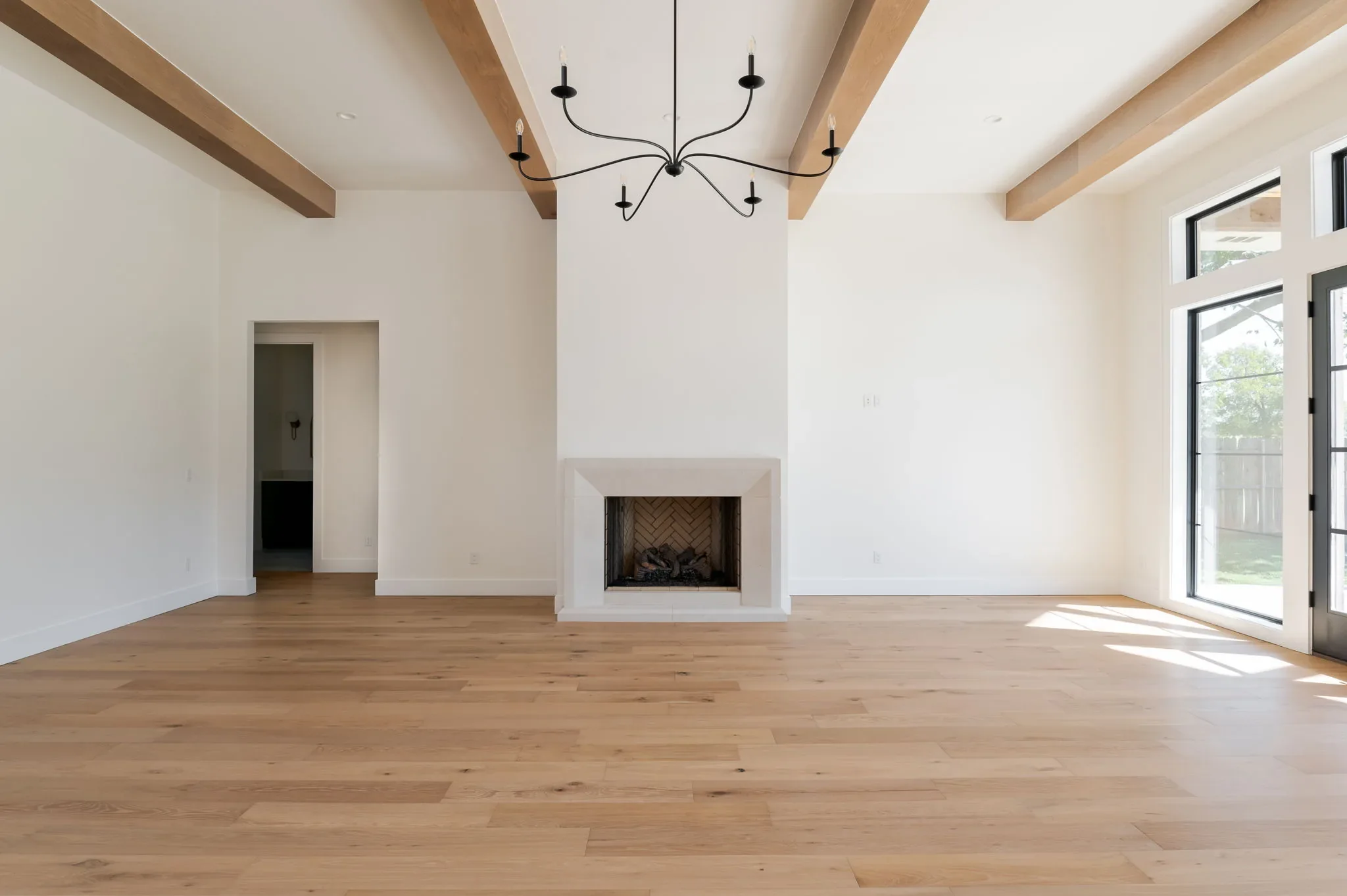 Great room with exposed wood beams, fireplace, and French doors