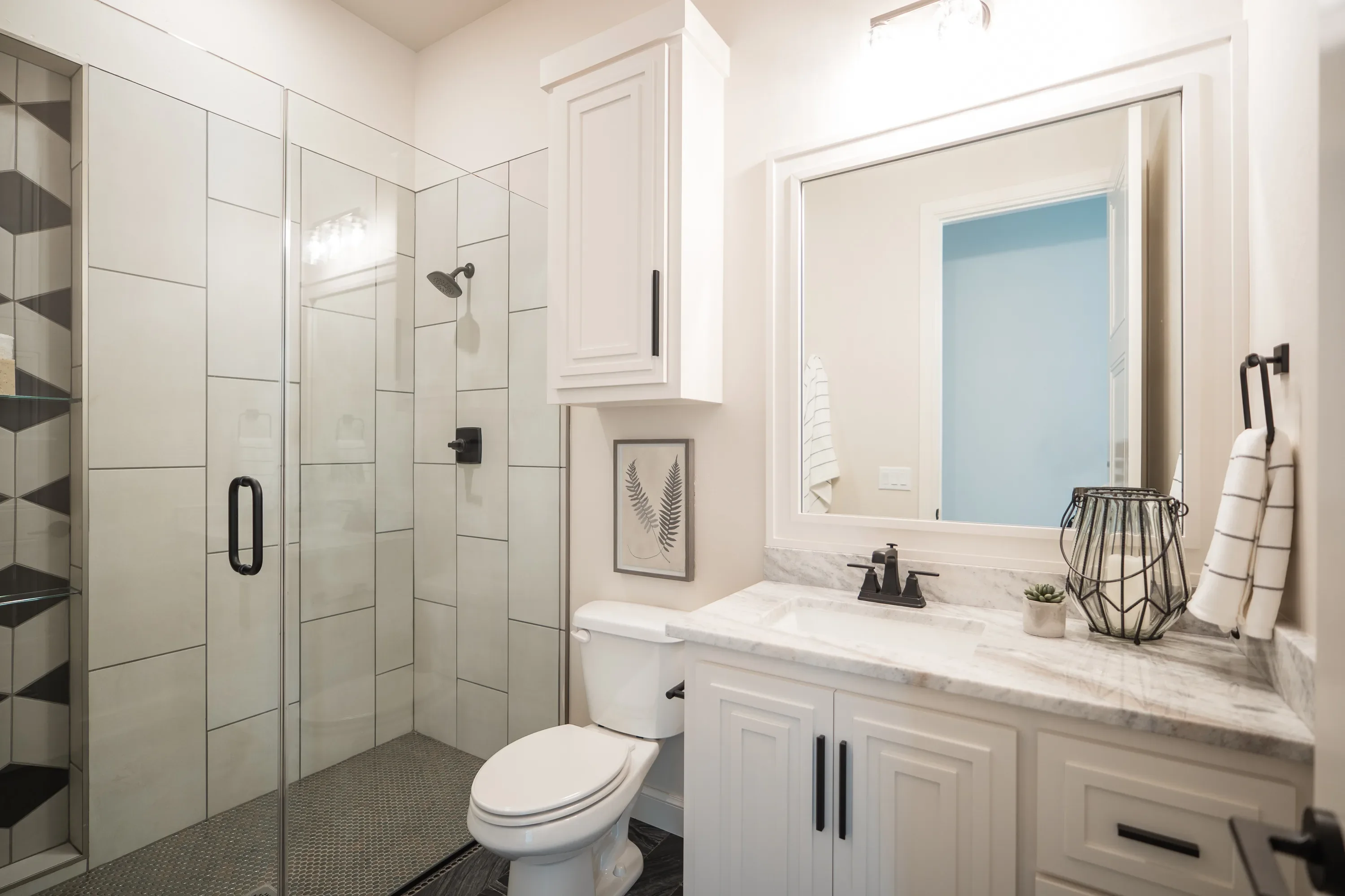 Guest bathroom with glass shower, white vanity, and black fixtures