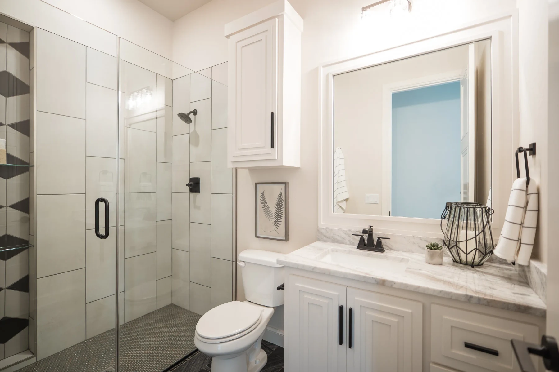 Guest bathroom with glass shower, white vanity, and black fixtures