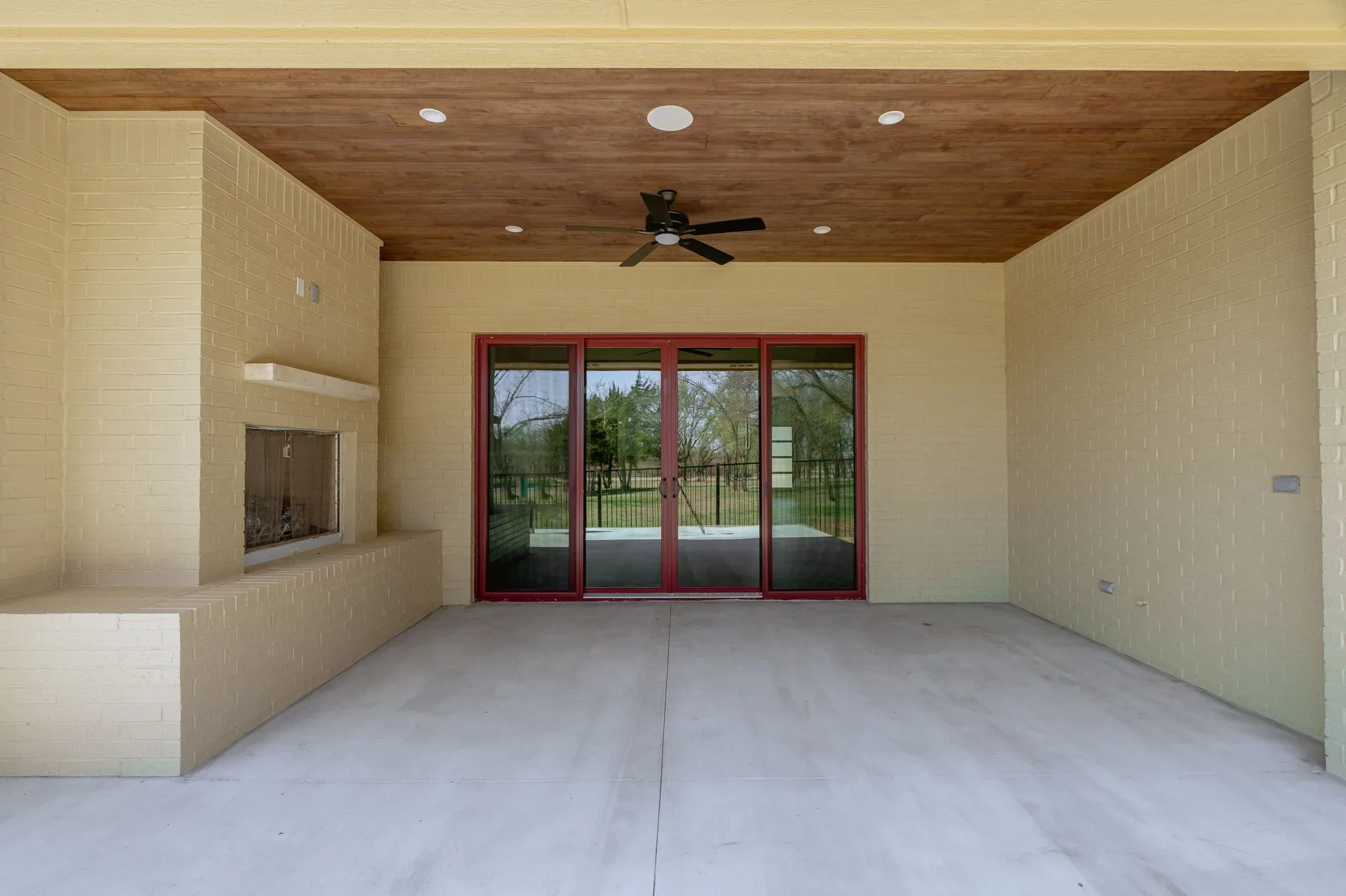 Covered rear patio with a fireplace and red-framed glass doors