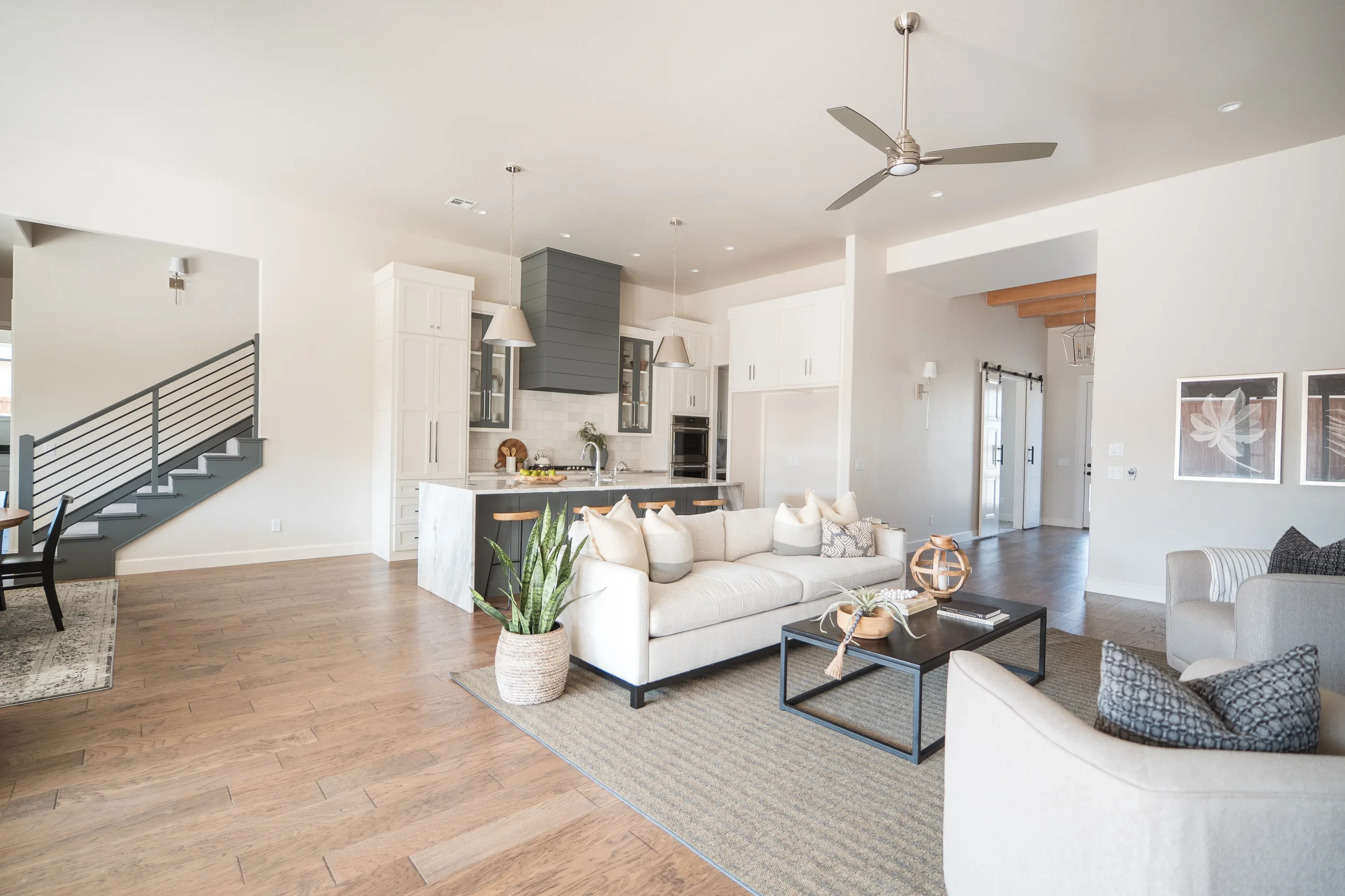 Open living room with warm wood floors and adjacent kitchen