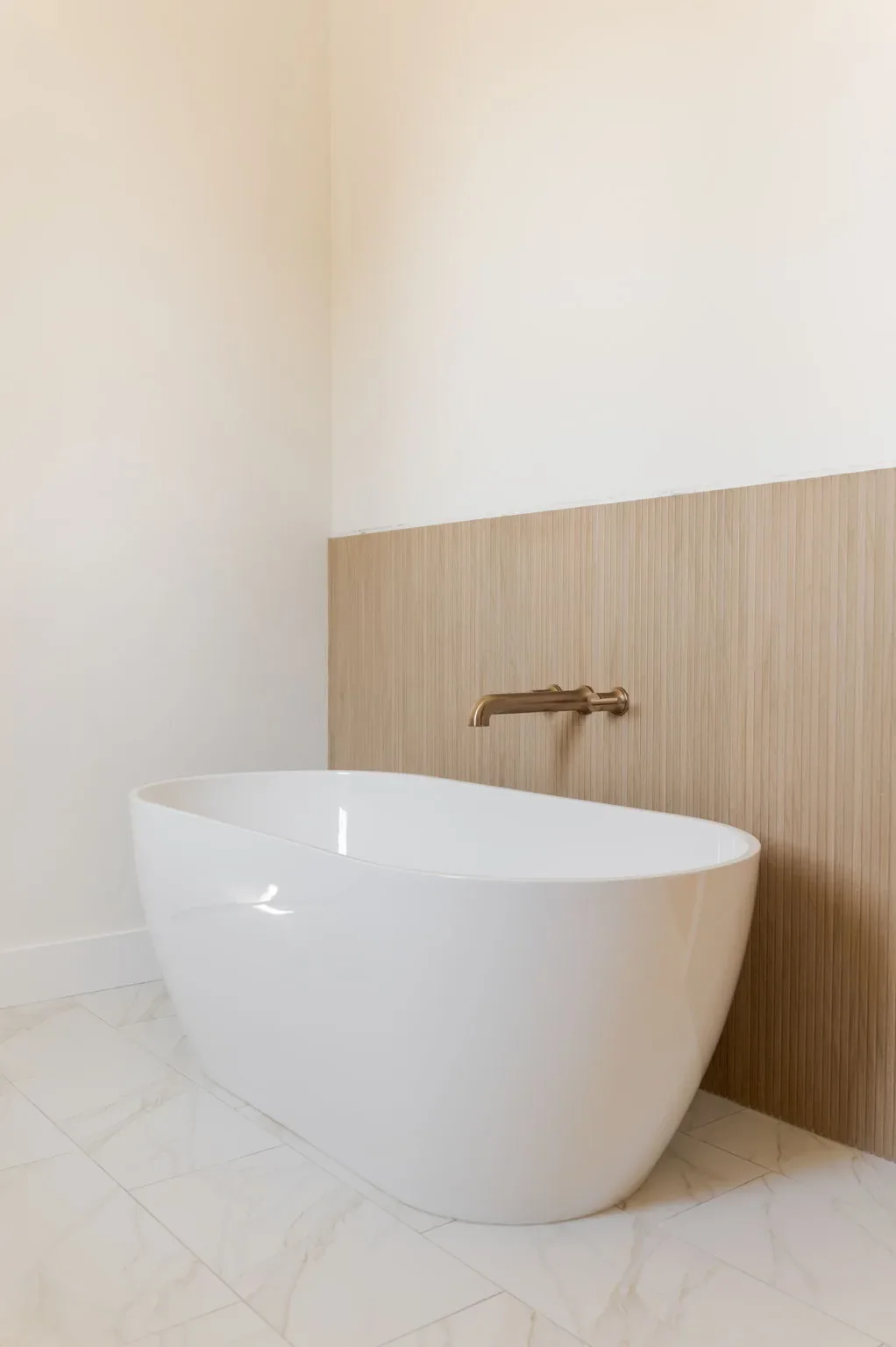 Freestanding tub against a warm wood-tile accent wall