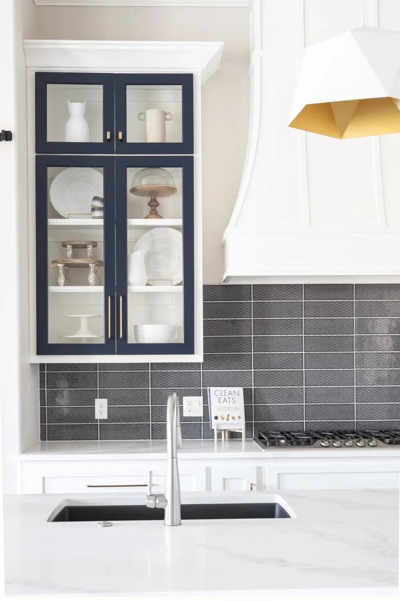Kitchen detail with black glass-front cabinets and dark tile backsplash