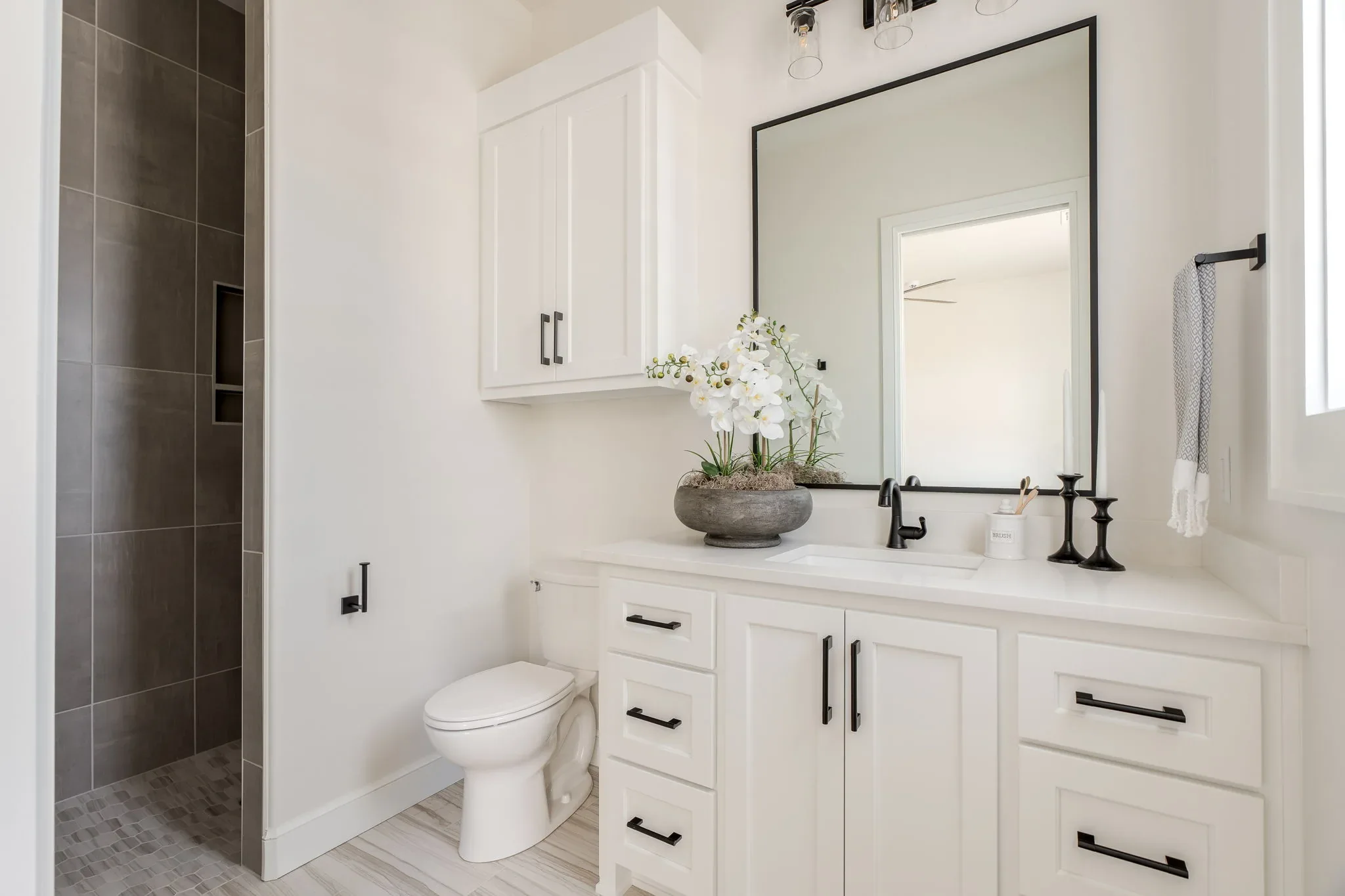 Bathroom with a dark tiled shower and white vanity