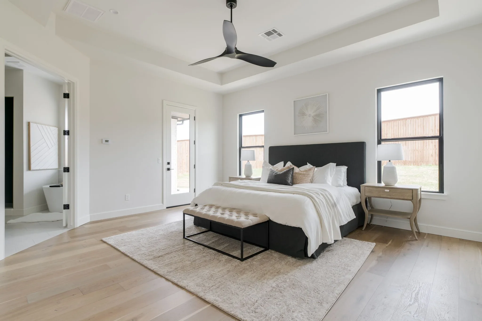 Primary bedroom with a tray ceiling and black fan