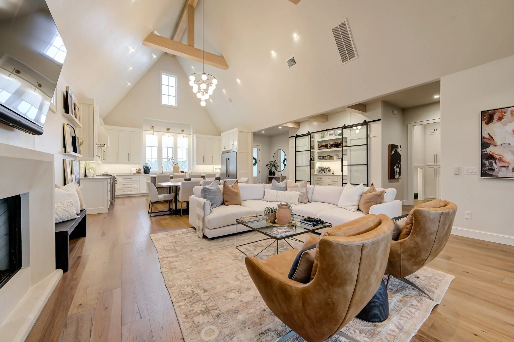 Vaulted great room with exposed beams, fireplace, and open kitchen
