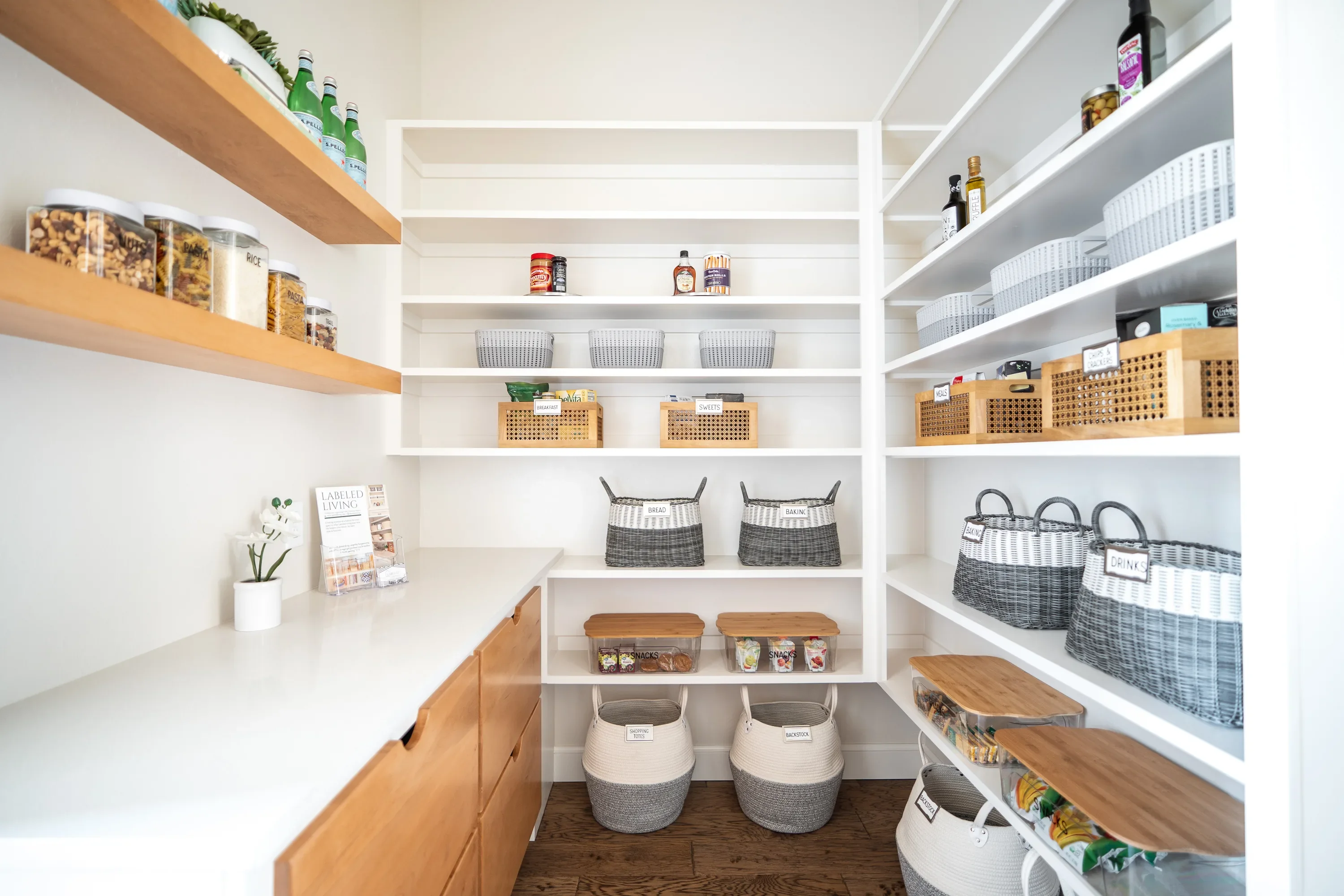Walk-in pantry with open shelving, labeled baskets, and wood drawers