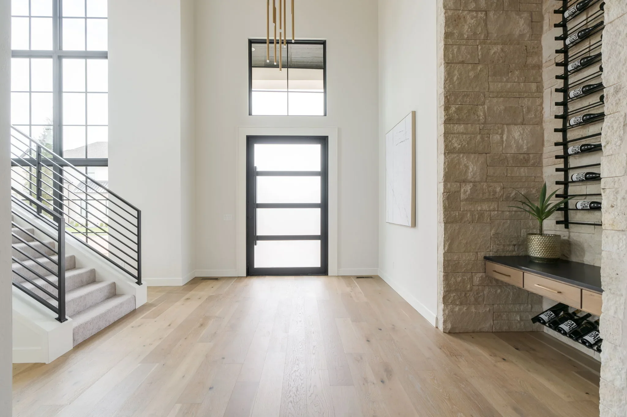 Two-story foyer with a floating staircase and stone wine wall