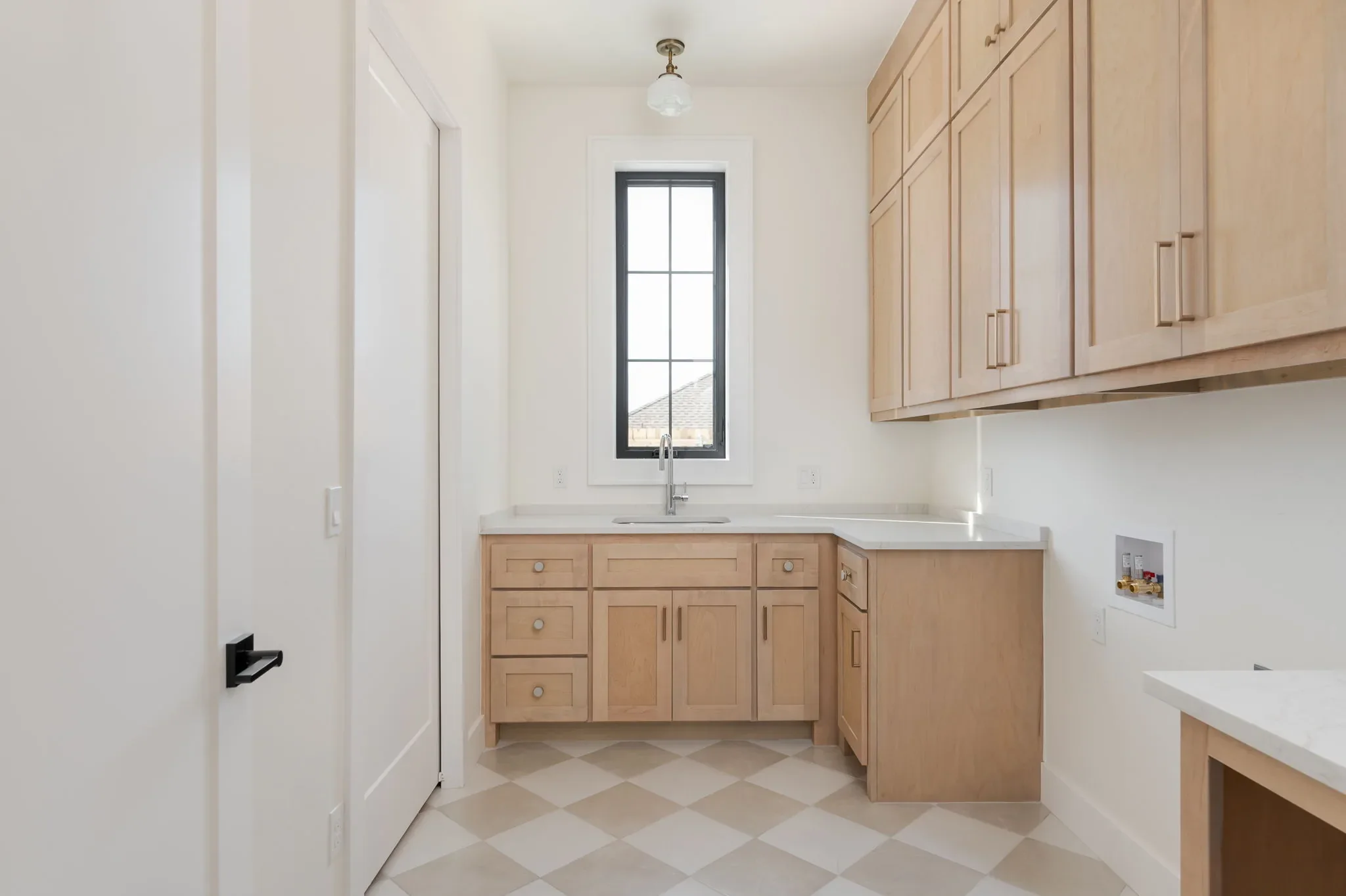 Laundry room with oak cabinetry and checkerboard tile flooring