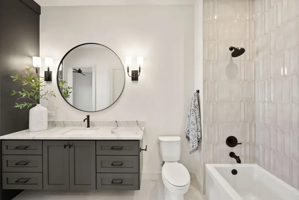 Guest bathroom with gray vanity, bathtub, and tiled shower
