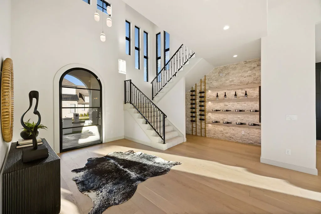 Double-height foyer with open staircase and stone wine wall