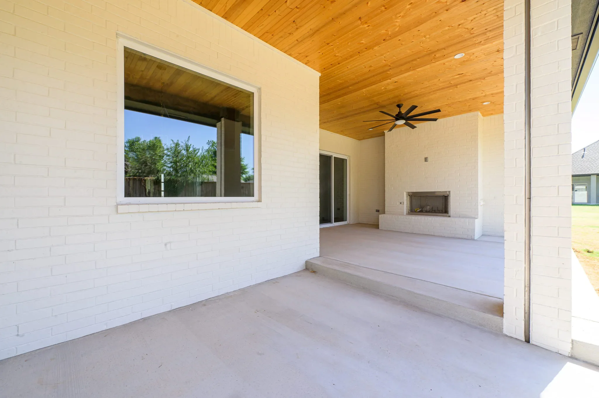 Covered patio with a pass-through window, fireplace, and wood ceiling