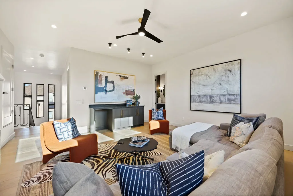 Sunlit living room with curved sectional and black fireplace wall