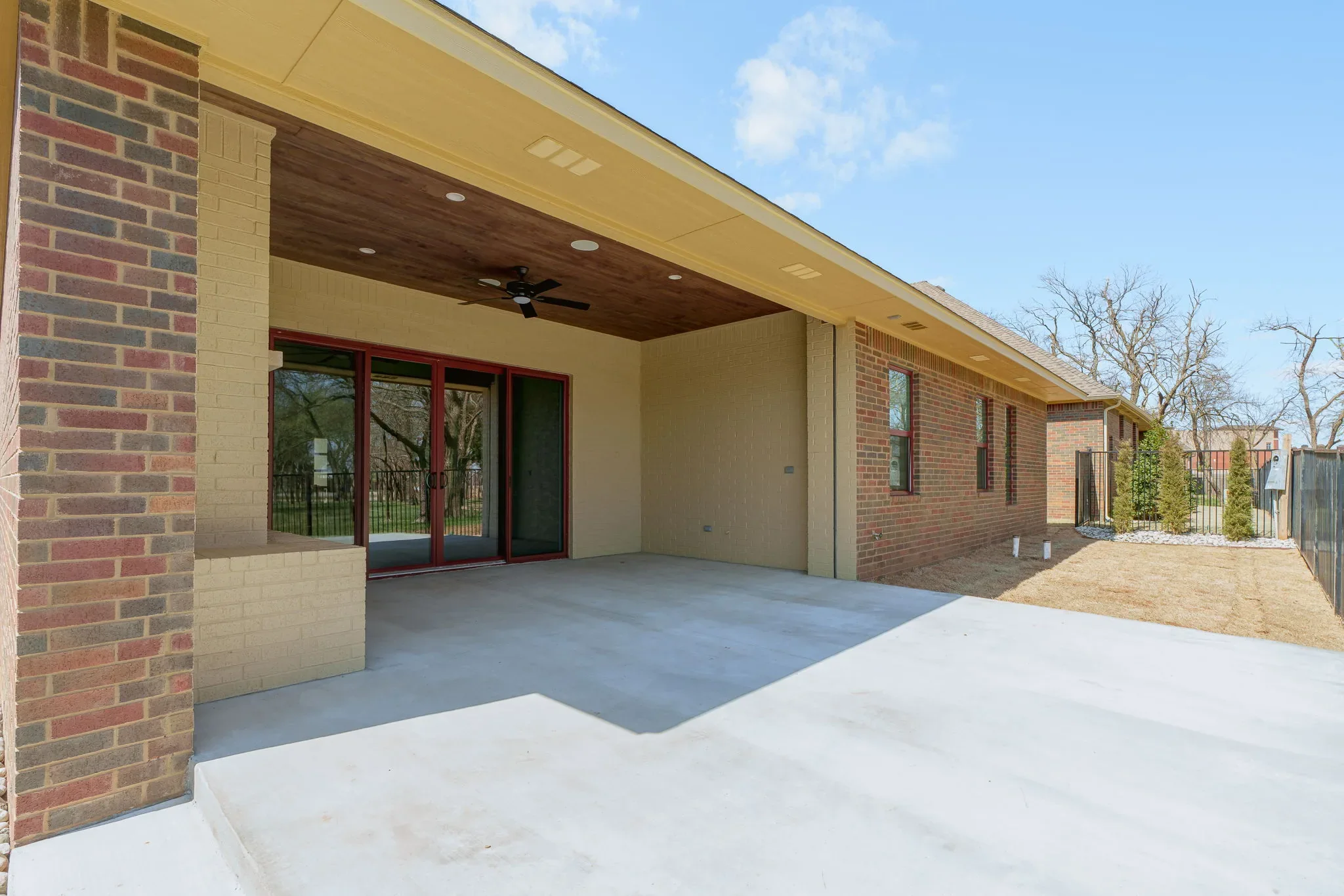 Covered rear patio with a wood ceiling, fireplace, and ceiling fans