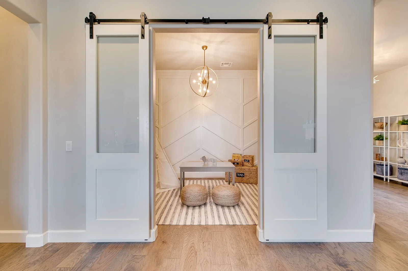 Flex room with frosted barn doors and geometric accent wall