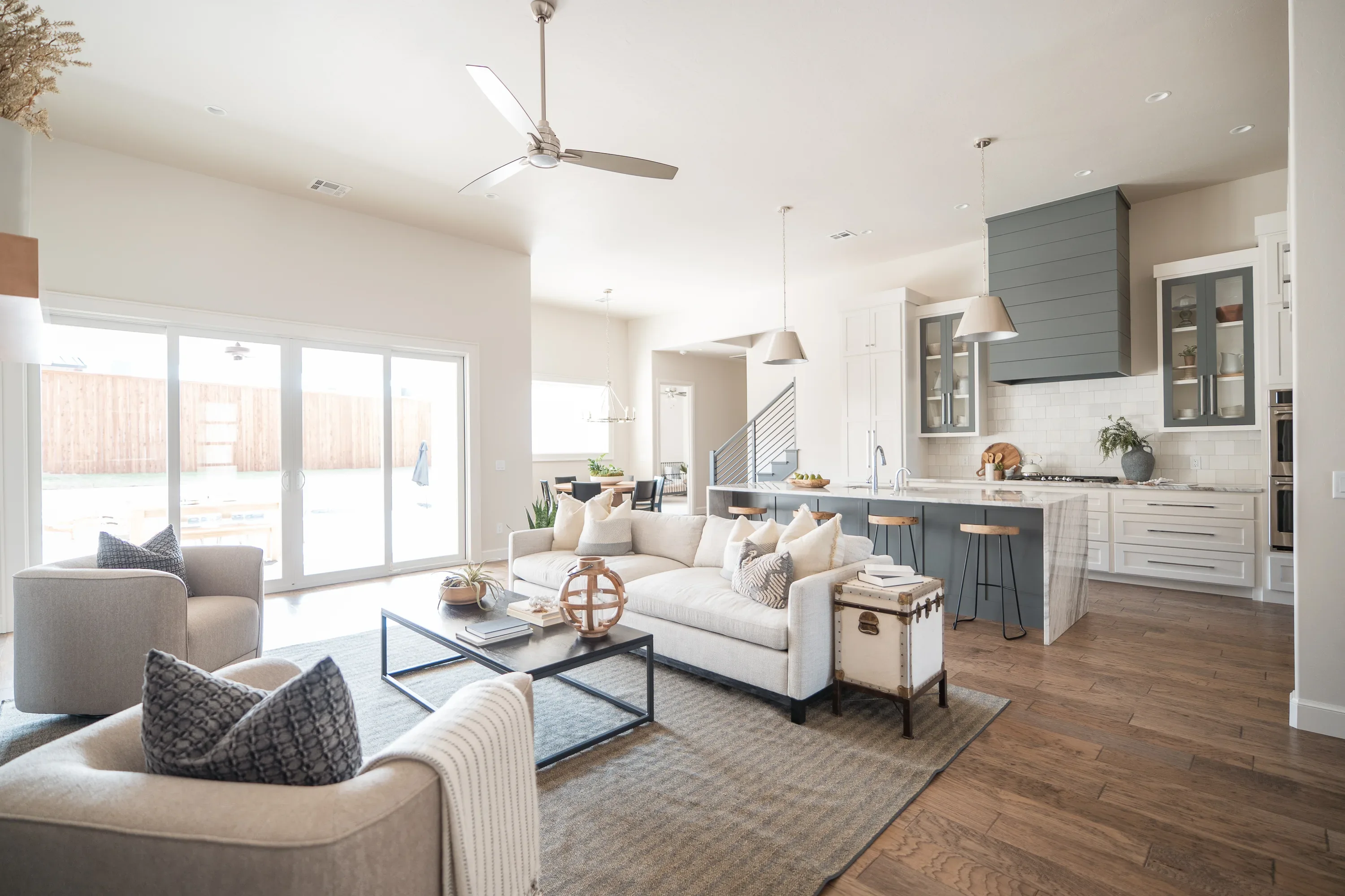 Living room and waterfall-island kitchen opening to backyard doors