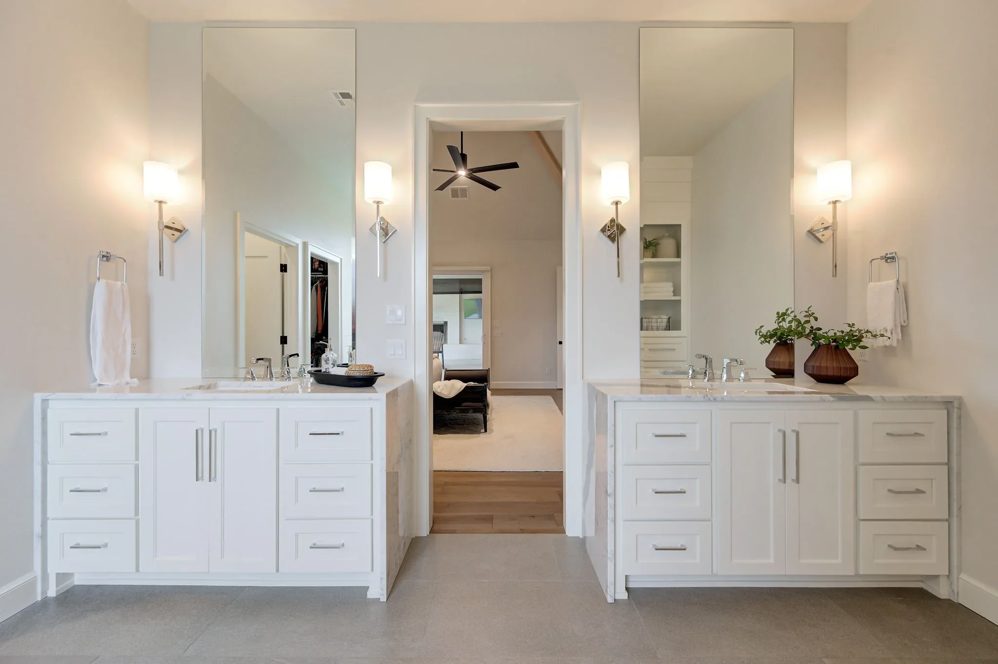 Primary bathroom with separate white vanities and tall mirrors