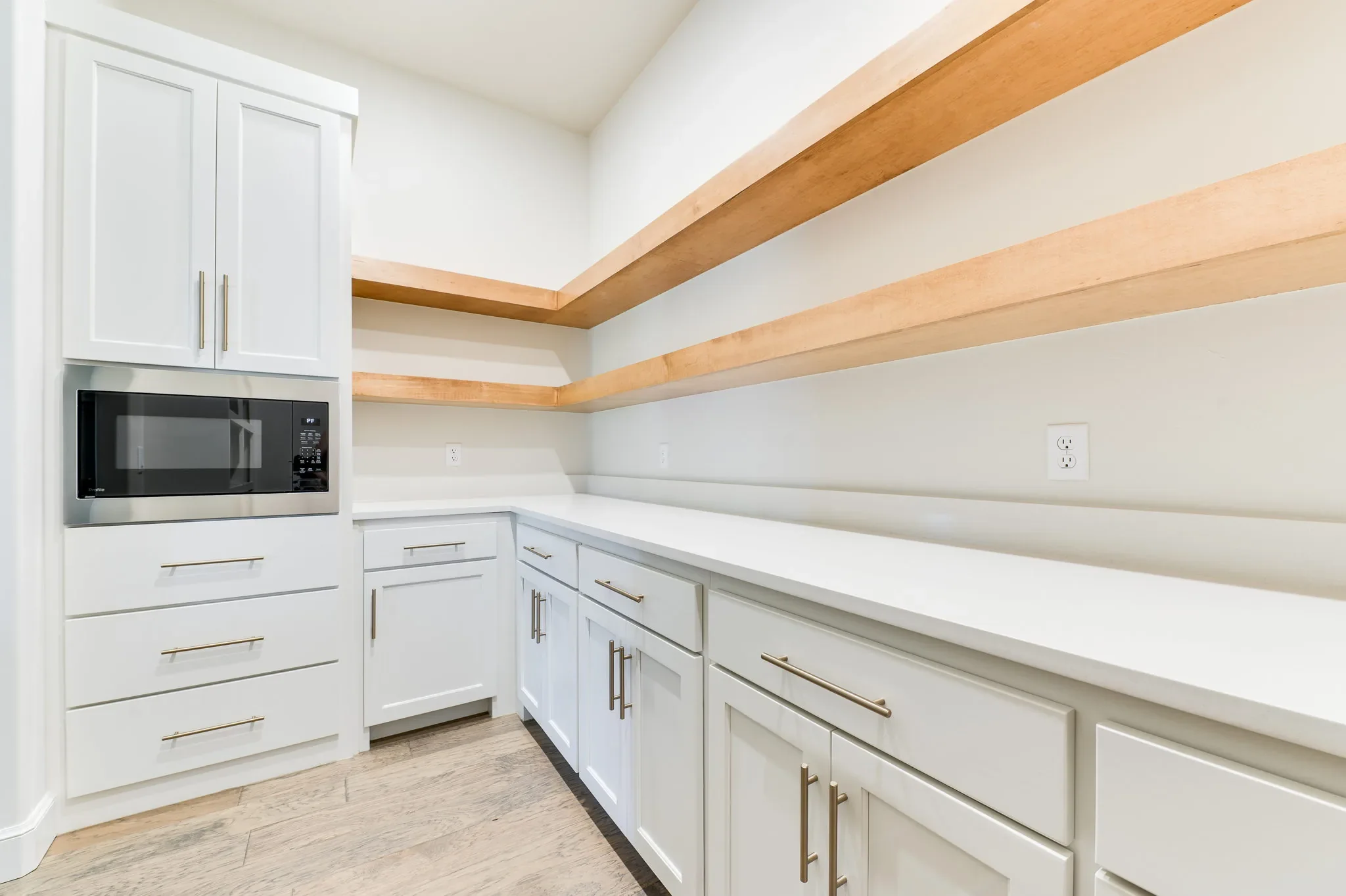 Walk-in prep pantry with long counters and wood shelving