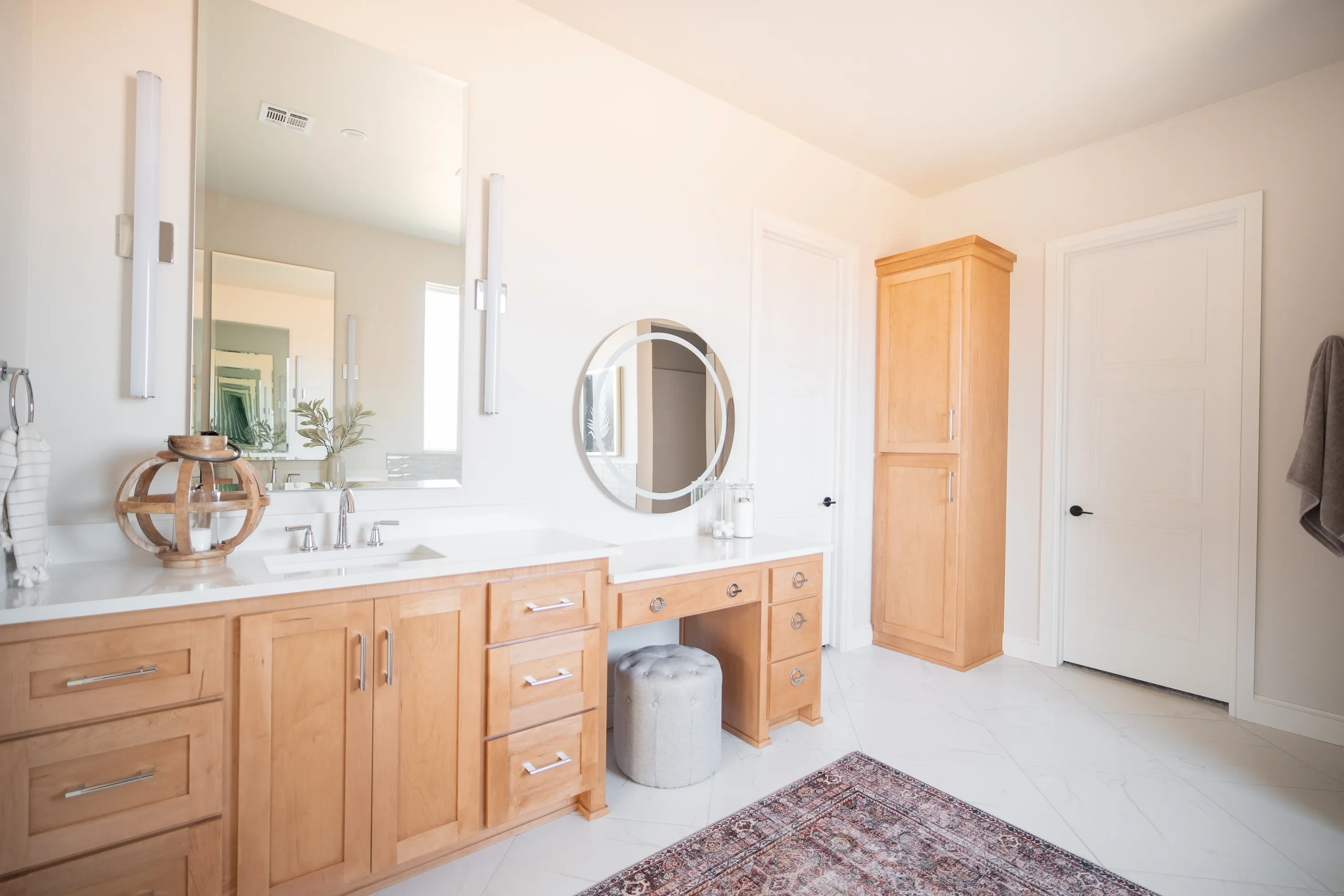 Primary bathroom vanity with wood cabinetry and round mirrors