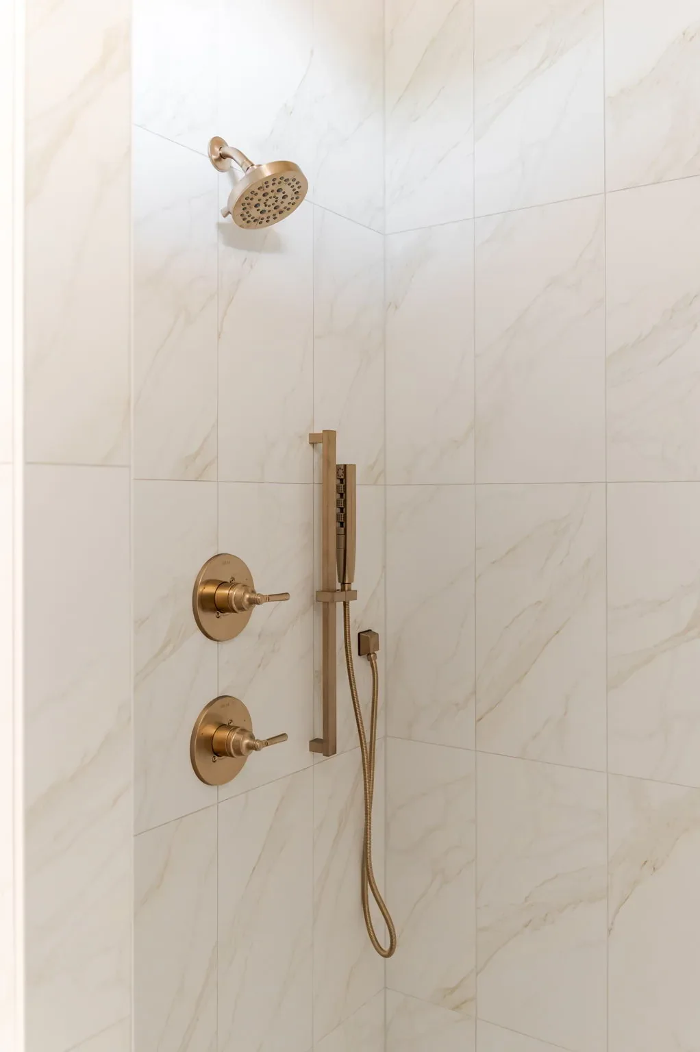 Brass shower fixtures against marble-look tile