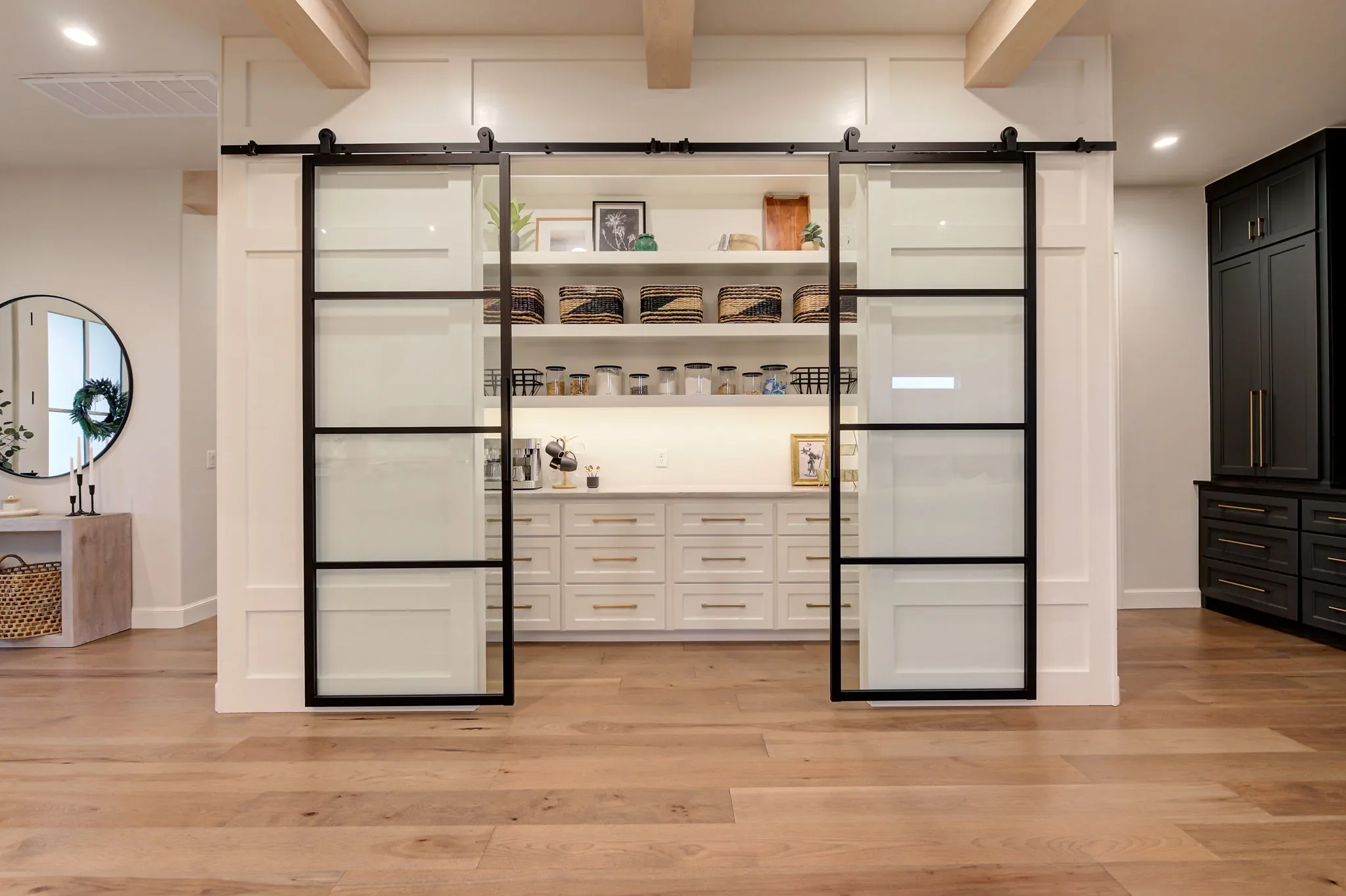 Walk-in pantry concealed behind black-framed sliding glass doors