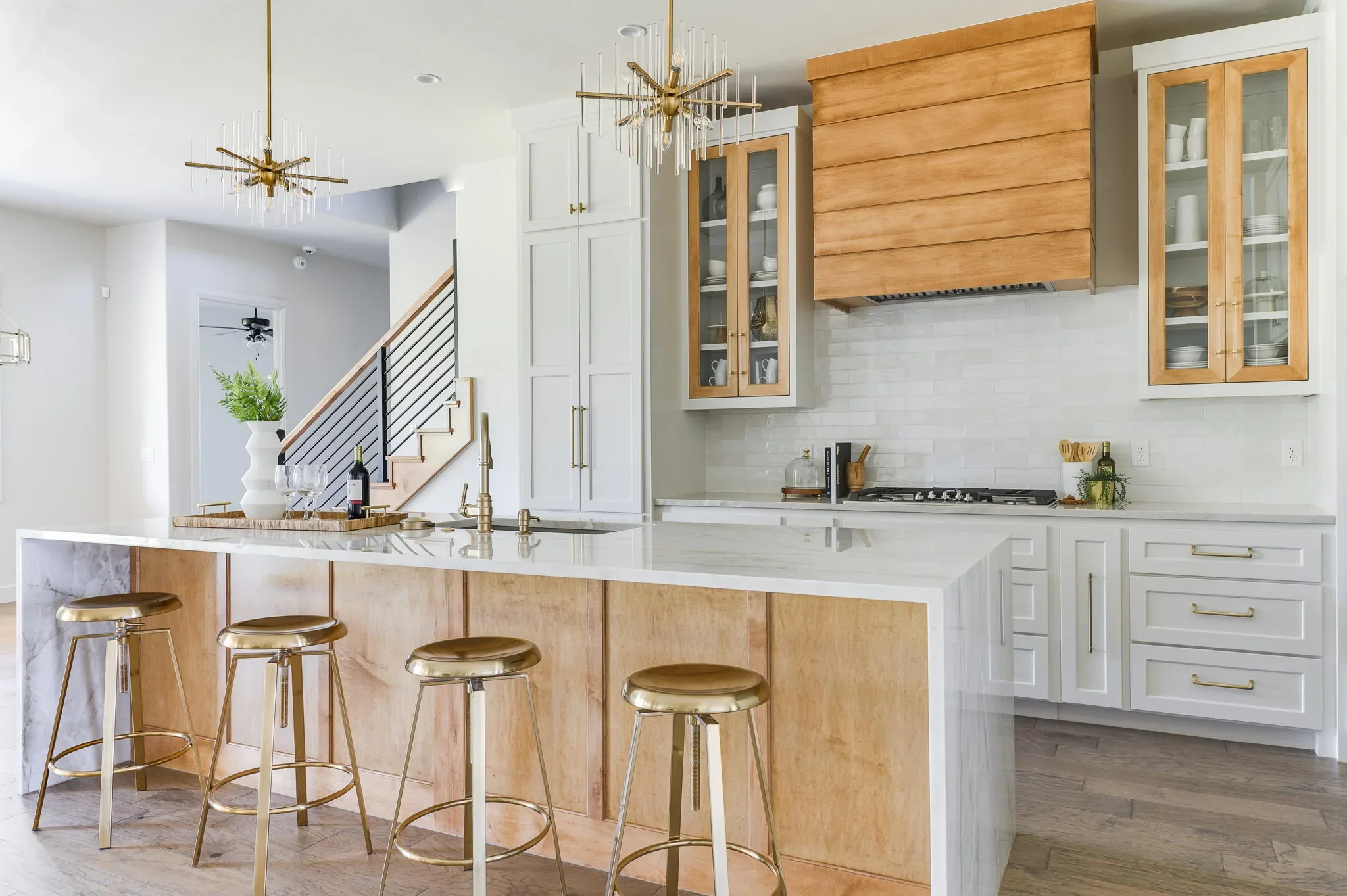 White kitchen with a wood accent hood and island seating